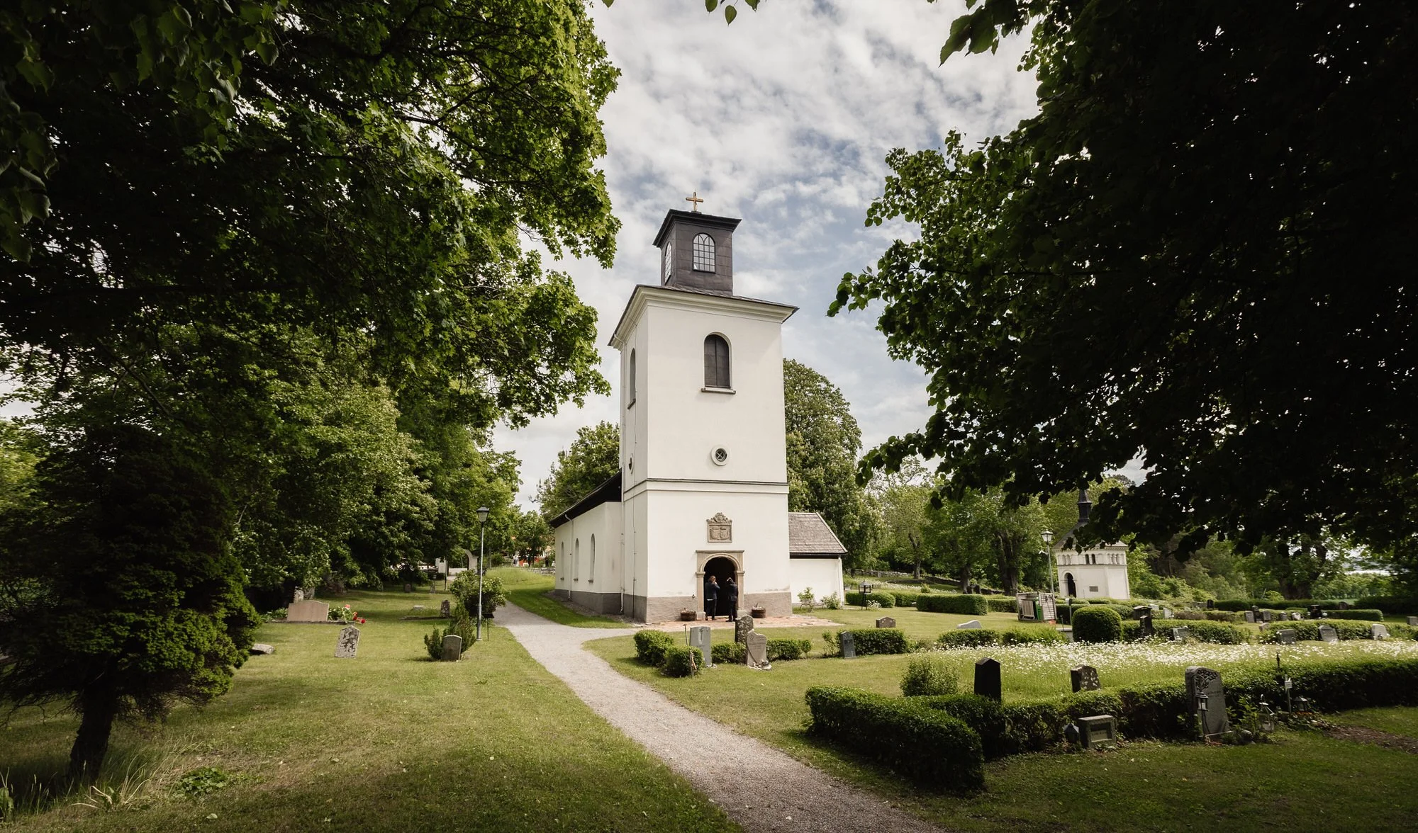 Låssa kyrka i Upplands-Bro med kyrkogård och lindar en sommardag