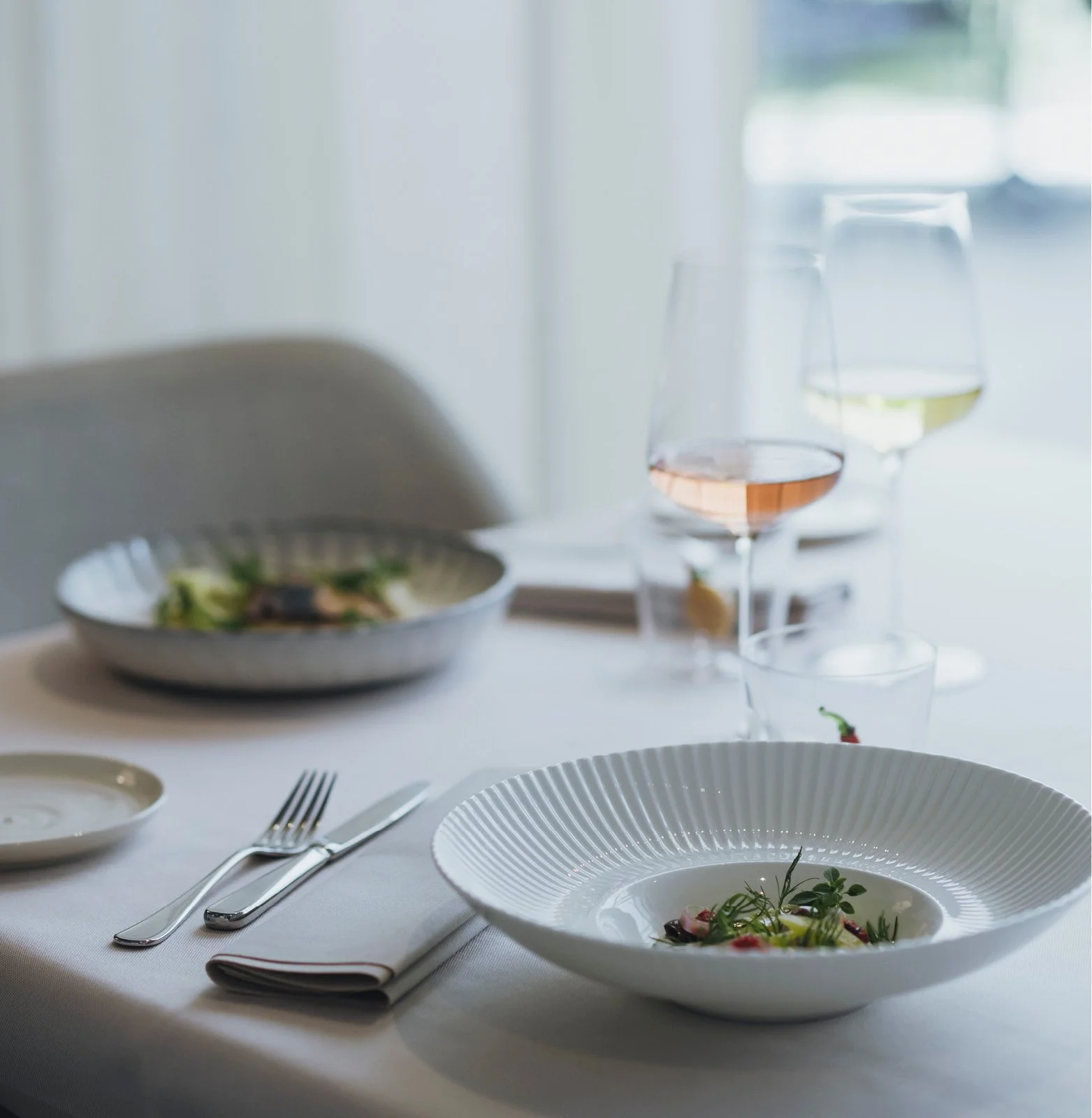 Tischszene mit mediterranen Speisen und Weinen im Restaurant ANIMO by Aigner