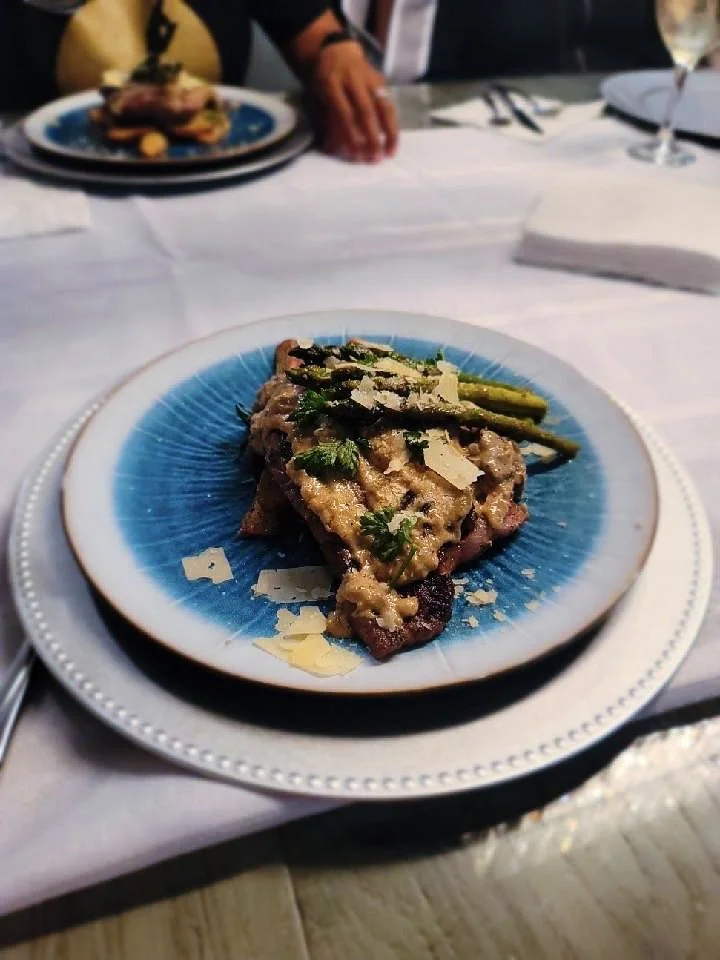 Ribeye Steak with Rosemary Potatoes topped with Mushroom and Onion Supreme Sauce and Parmesan with a side of asparagus