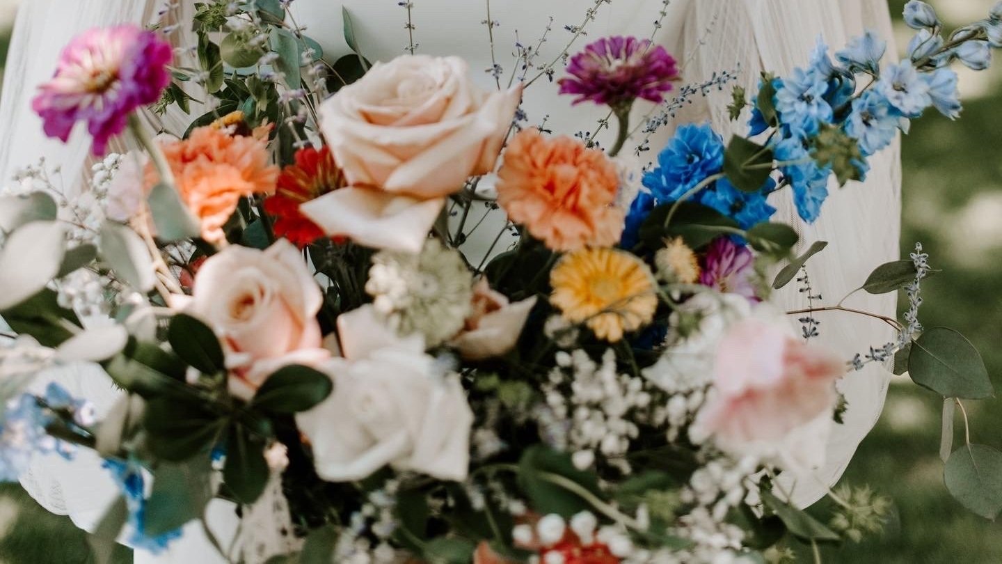 A colorful bouquet of various flowers including roses, carnations, baby's breath, and blue delphiniums.