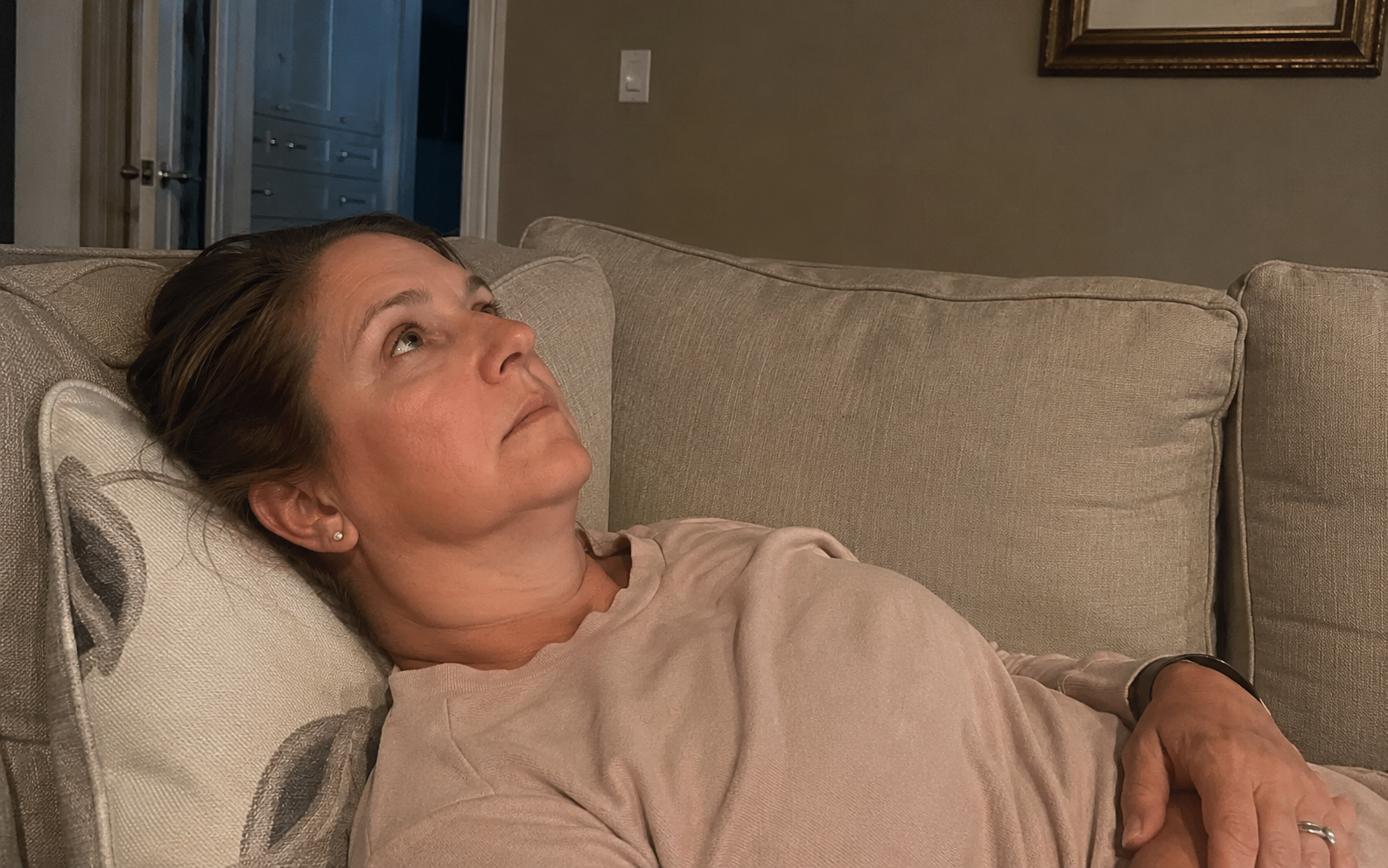 "Woman lying on a couch staring at the ceiling unable to rest — burnout guilt and perfectionism in high-achieving women in midlife"