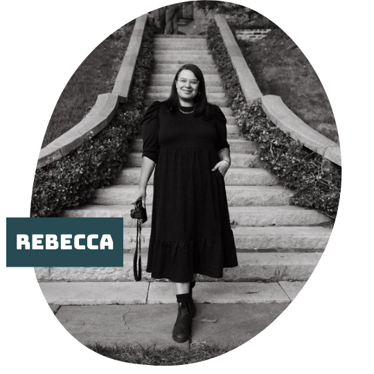A woman in a black dress and boots descending garden stairs with a camera in their hand