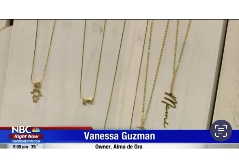 Display of gold necklaces with various pendants, including a crab, a dog, and a word pendant spelling 'Mama.'