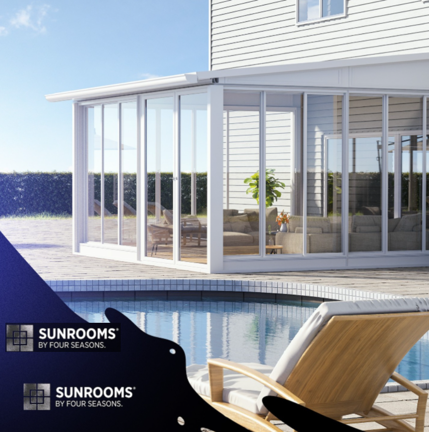 A modern glass sunroom attached to a house with a view of a backyard pool and outdoor furniture, including a sunlounger and sofa with cushions, during daytime.