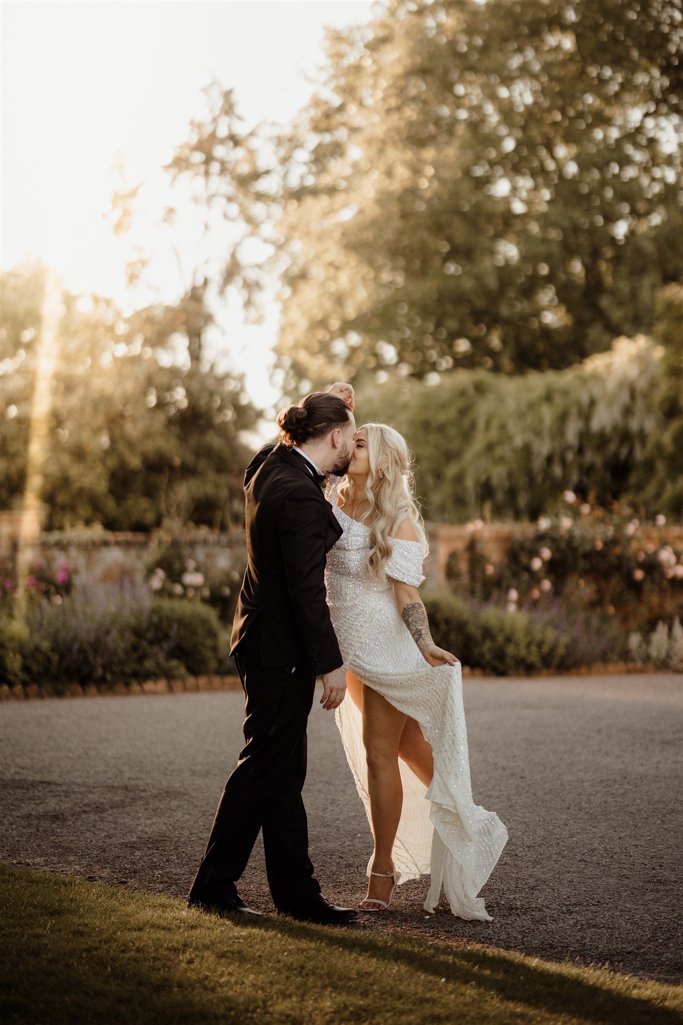 Bride in sparkly wedding dress and groom in tuxedo kissing