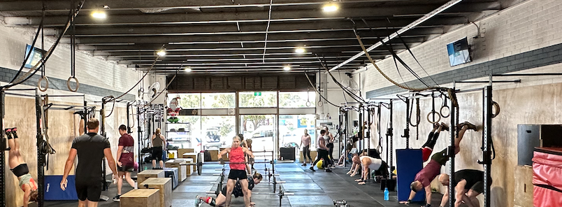 People working out in a CrossFit gym in Belconnen with rings and workout equipment