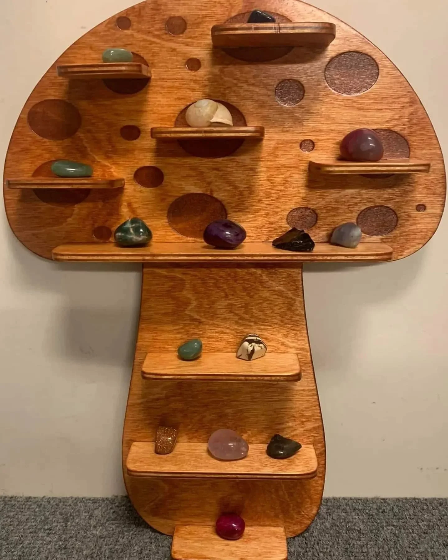 Decorative wooden display in the shape of a T-shape with various polished stones placed on and around it.