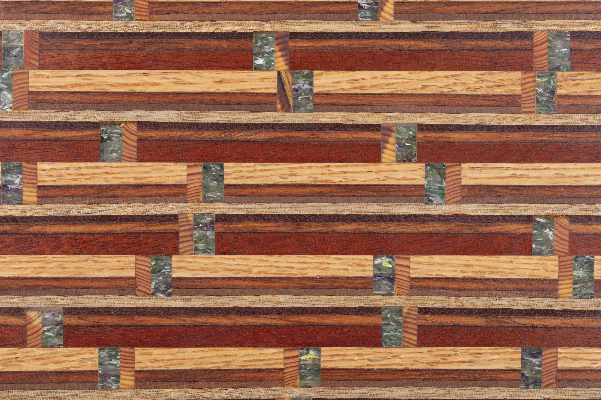 A close-up view of a wooden surface with an intricate pattern of rectangular wood pieces in different shades of brown, separated by narrow strips of iridescent glass or quartz.