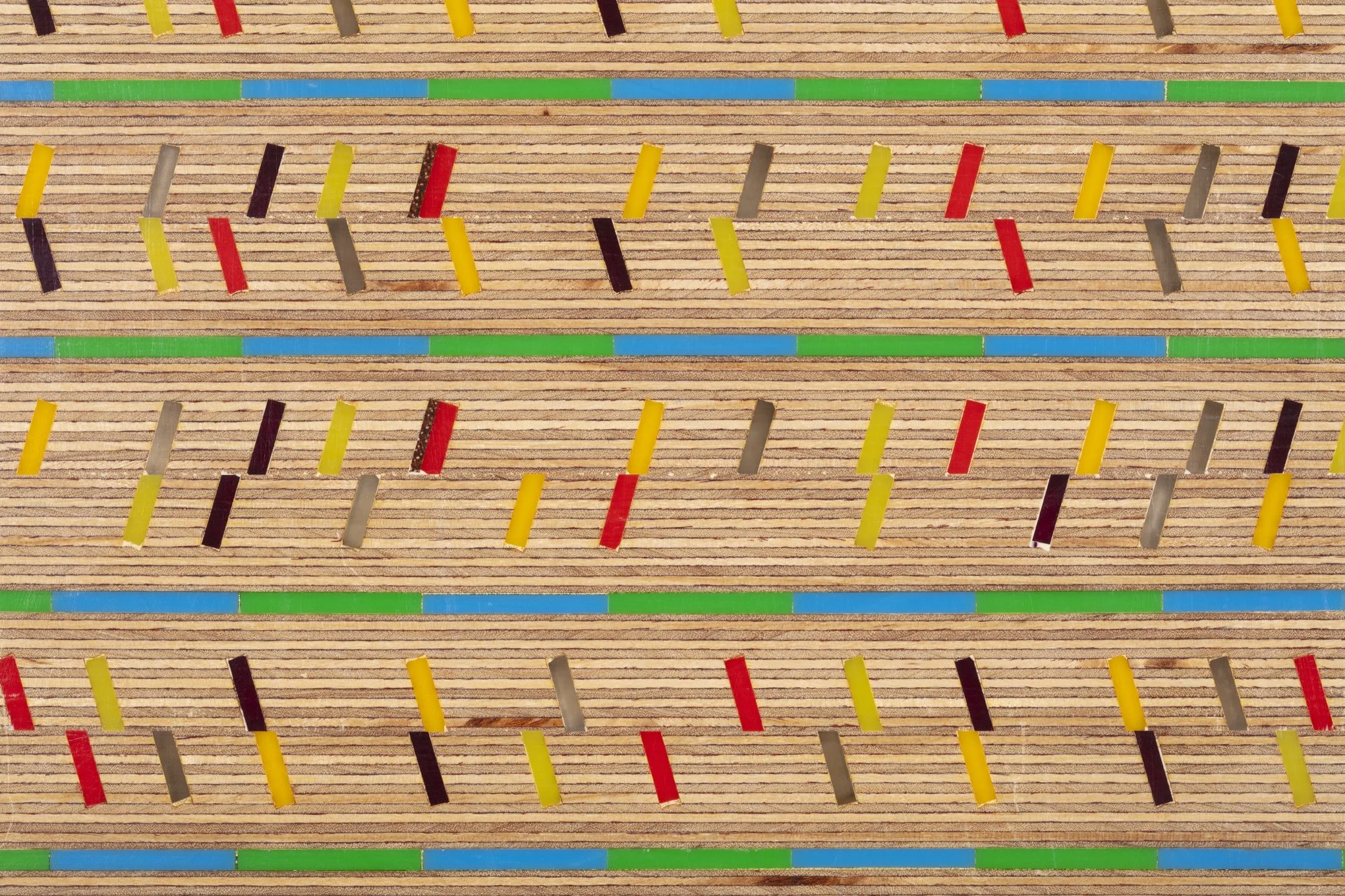 Close-up of a wooden game board with small colored pieces in yellow, red, gray, black, and green arranged in a grid pattern.