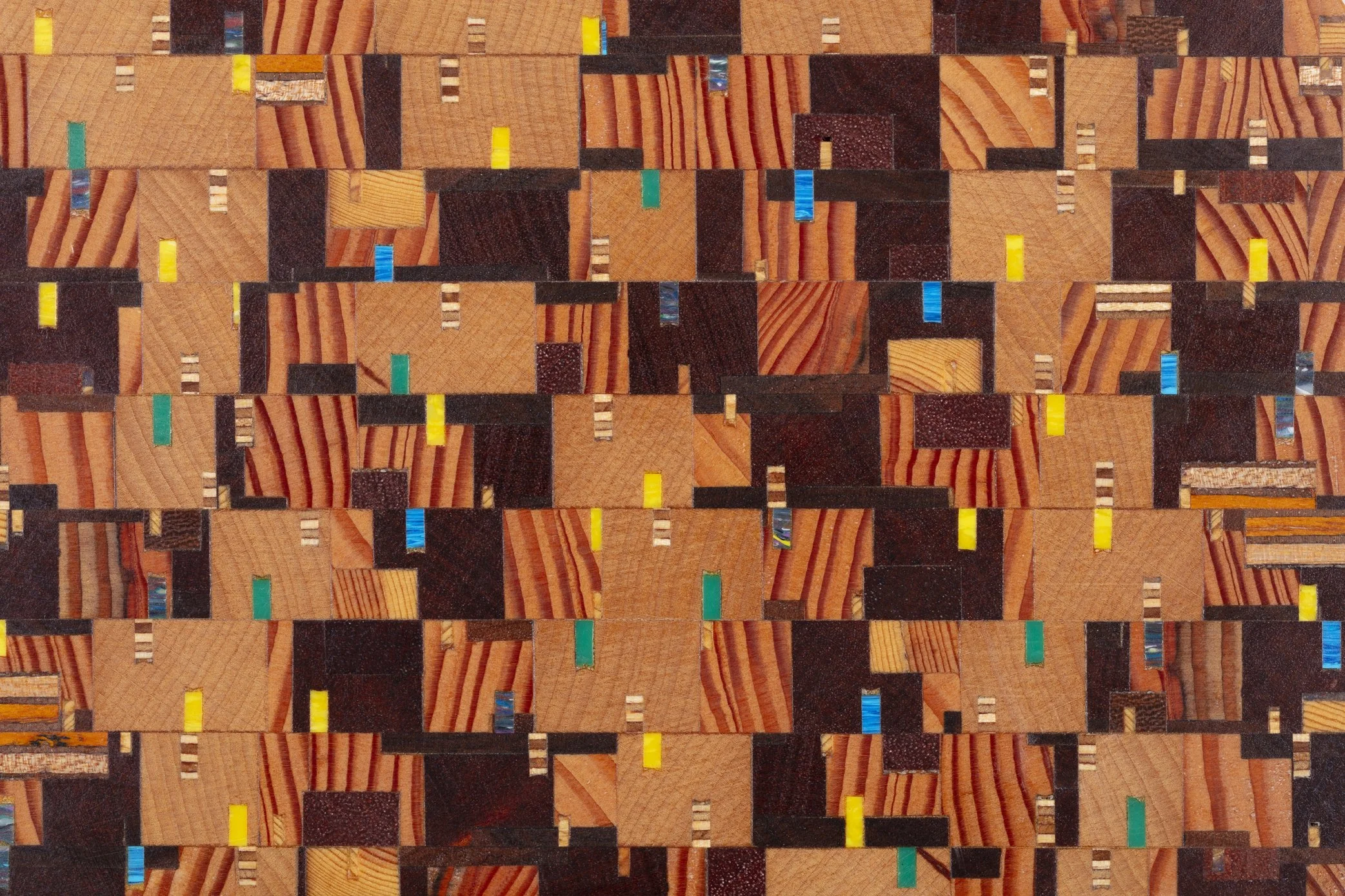 A patterned wooden mosaic with small rectangular pieces in various shades of brown, black, and some bright colors like yellow, teal, and blue.
