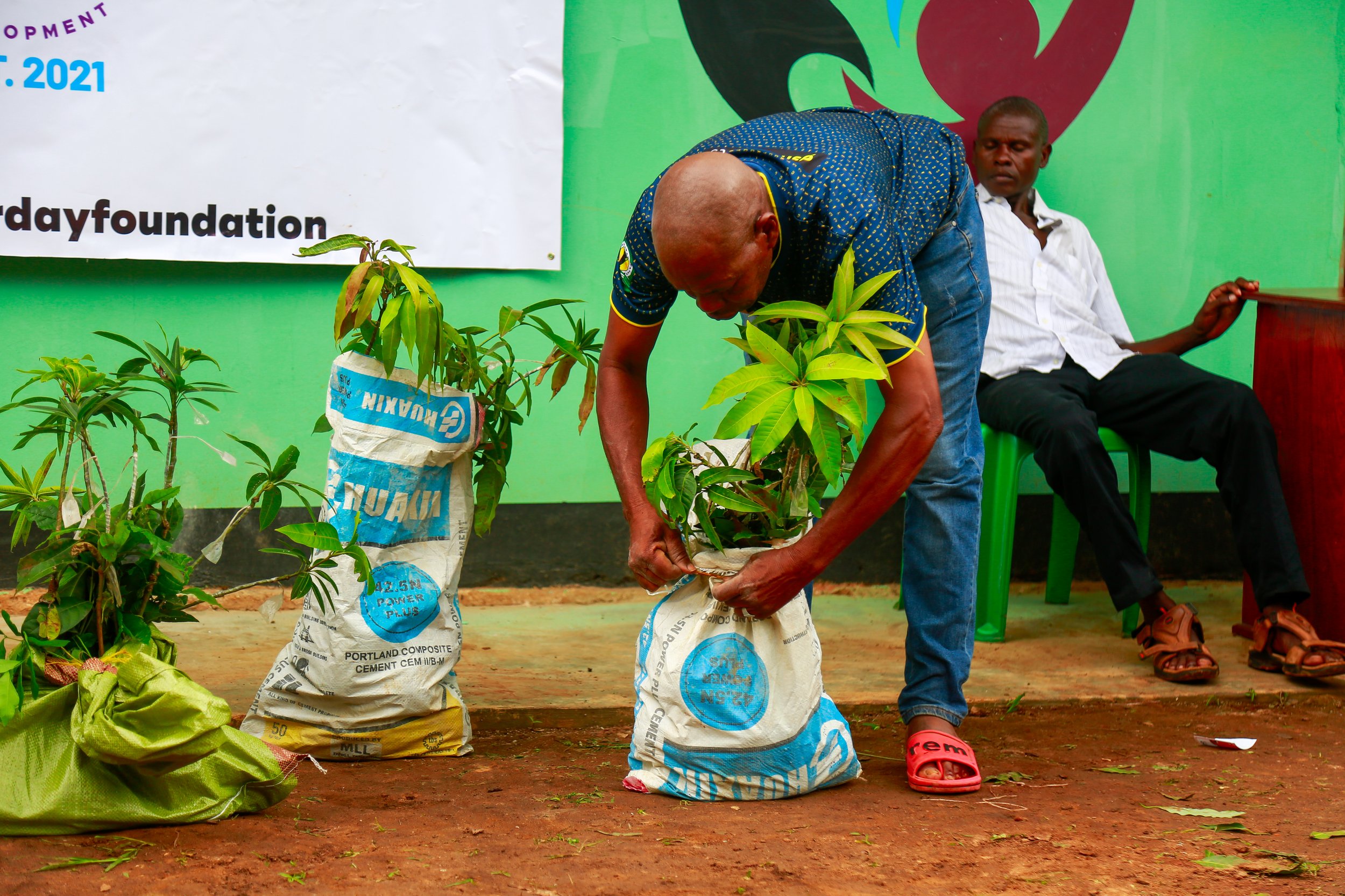 Man bends over bag of seedlings in Tanzania