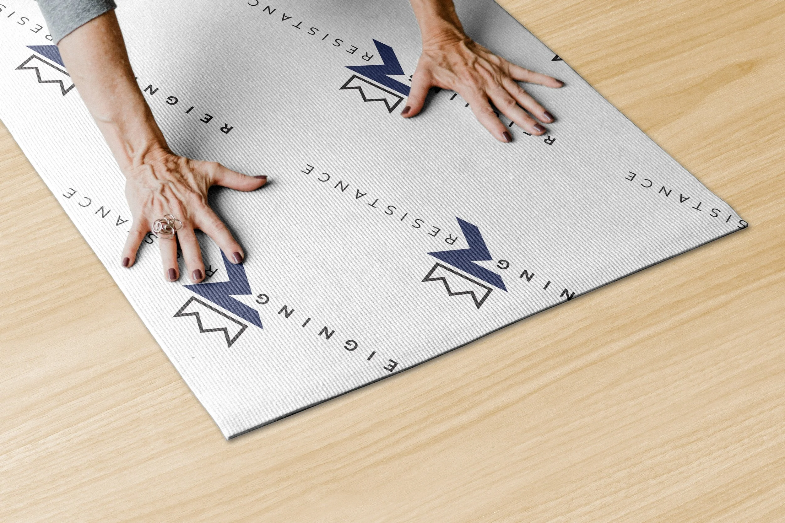 Person’s hands smoothing red and white textured material with printed logos and text on a wooden surface.