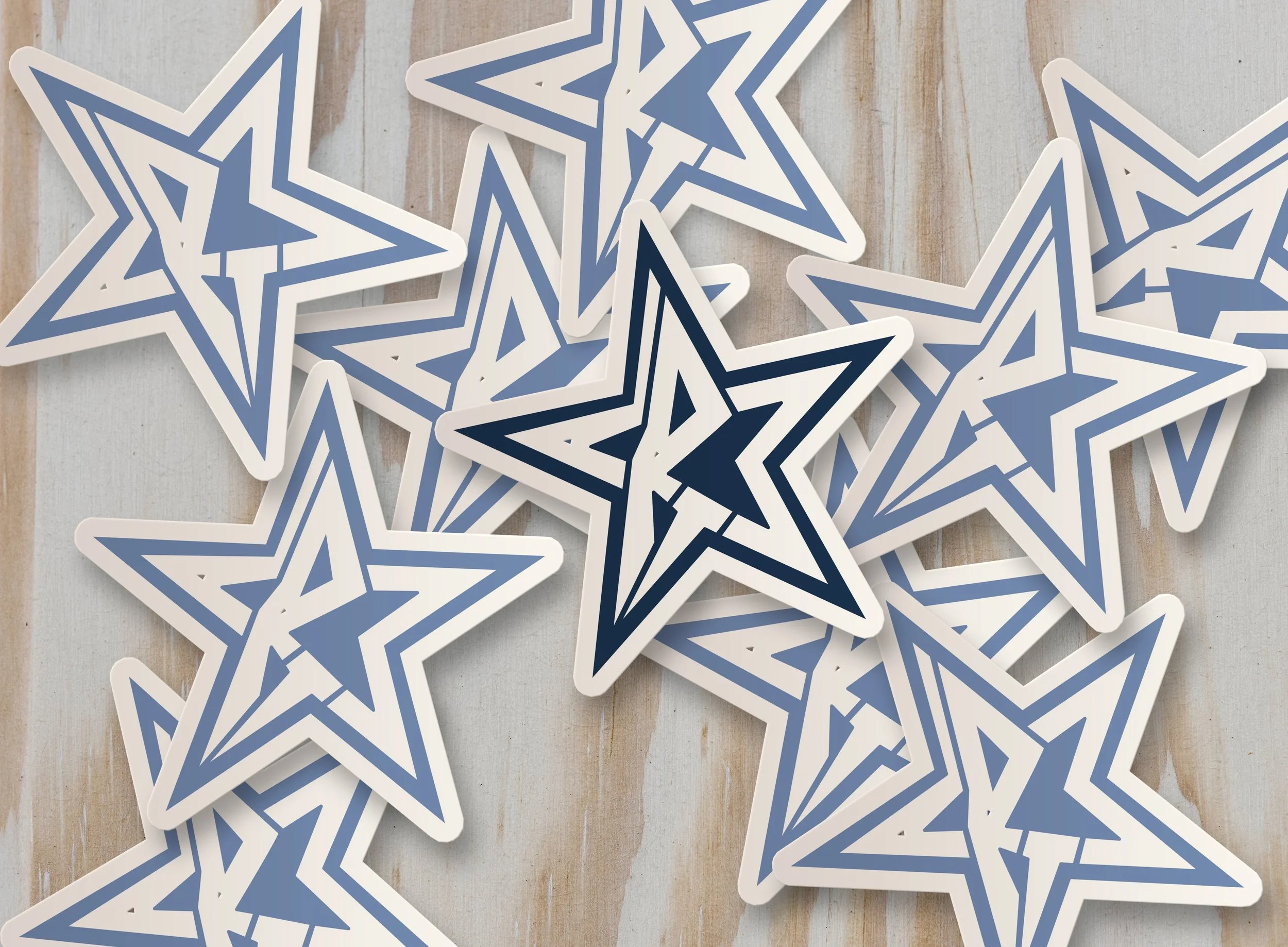 Multiple star-shaped stickers in white, blue, and black colors overlapping on a wooden surface.