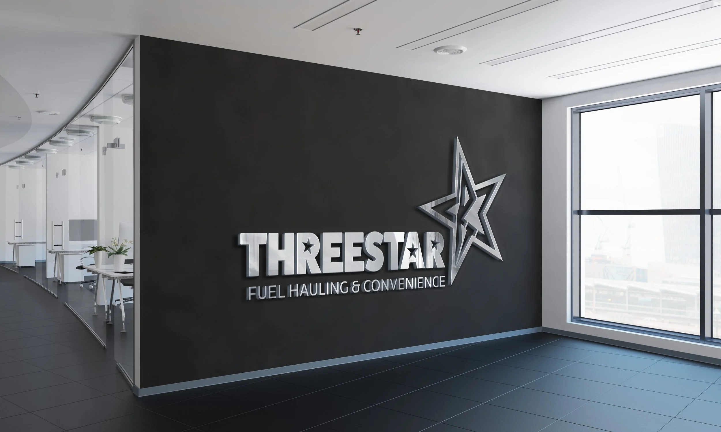 Interior of a modern office with a black wall displaying a sign that reads 'THREESTAR Fuel Hauling & Convenience' with a star logo, large windows on right, and a curved glass partition on left.