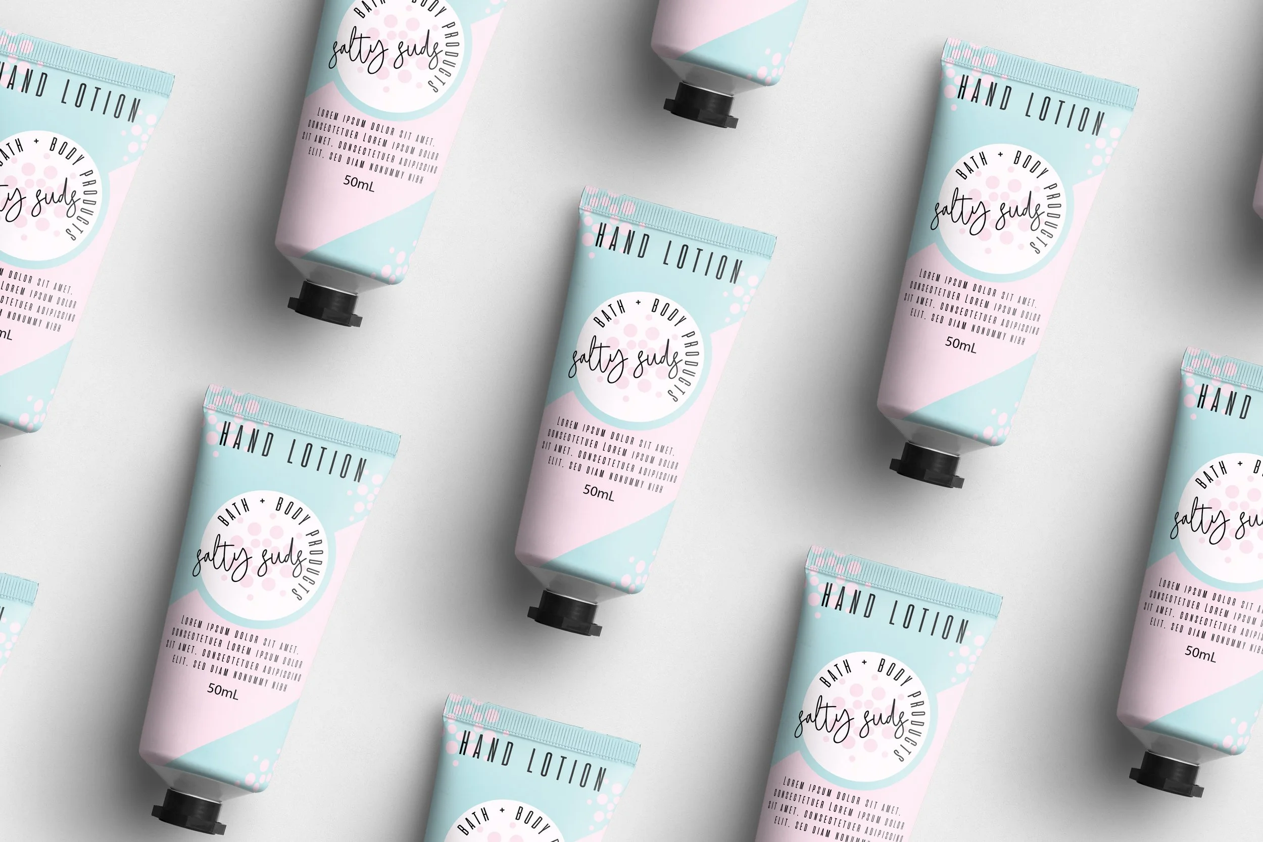 Multiple tubes of bath and body lotion labeled "salty suds" with pastel blue and pink packaging on a gray surface.