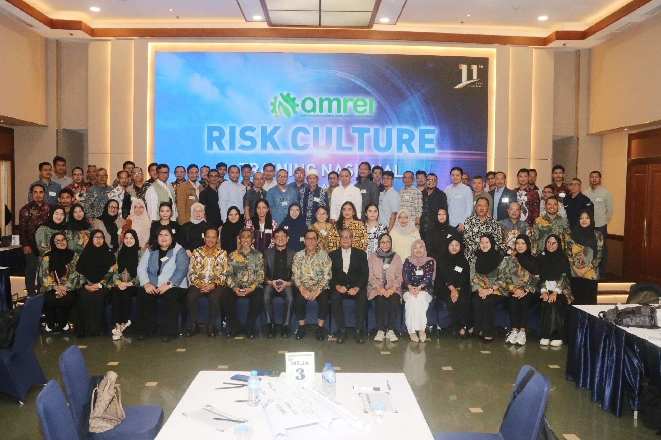 Group of people posing for a photo on stage at a conference with a large screen behind them that reads 'amrei RISK CULTURE' and '11th' anniversary logo.