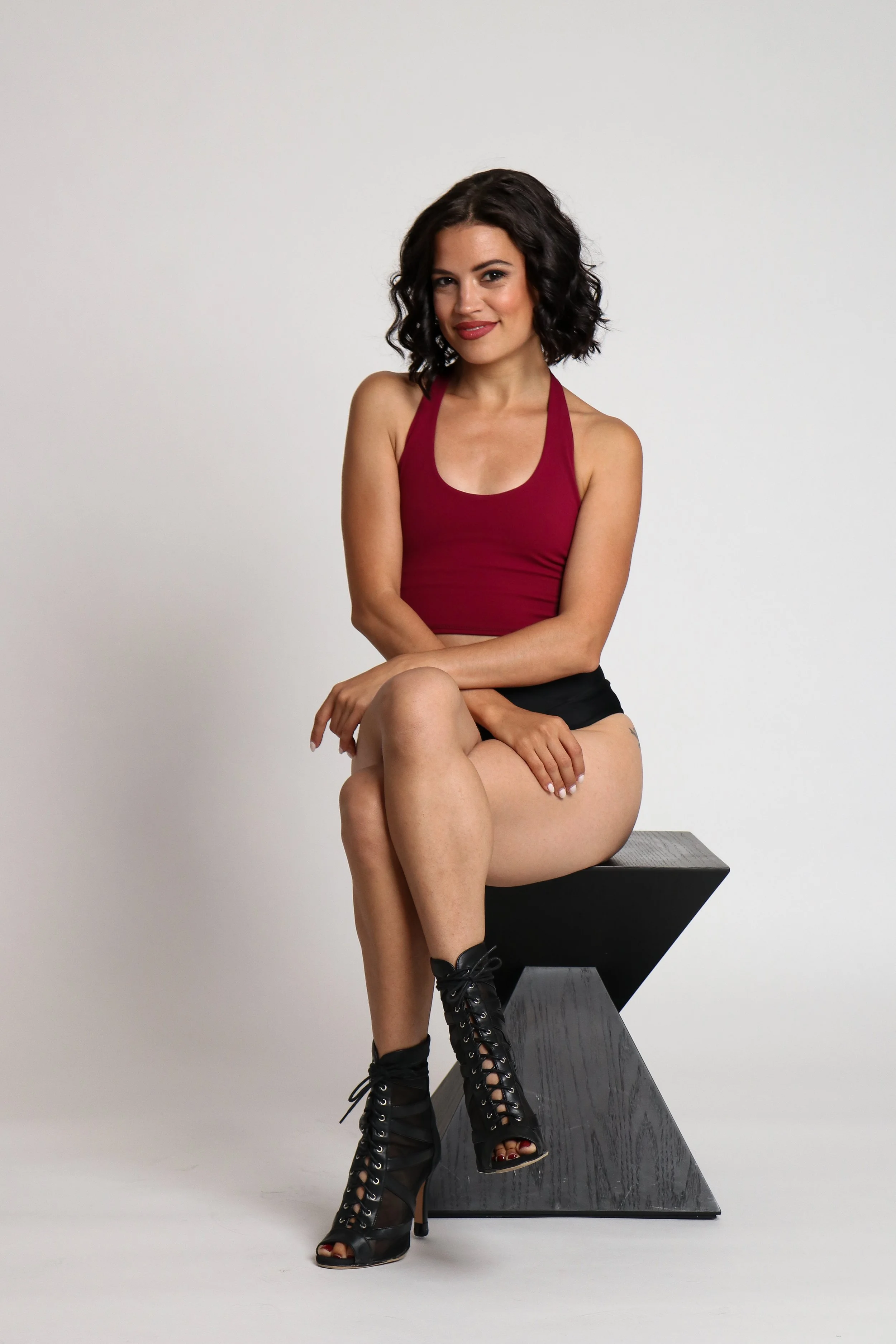 Shaka wearing fishnets and a black bra, extending her leg and arm in a sensual and creative way
