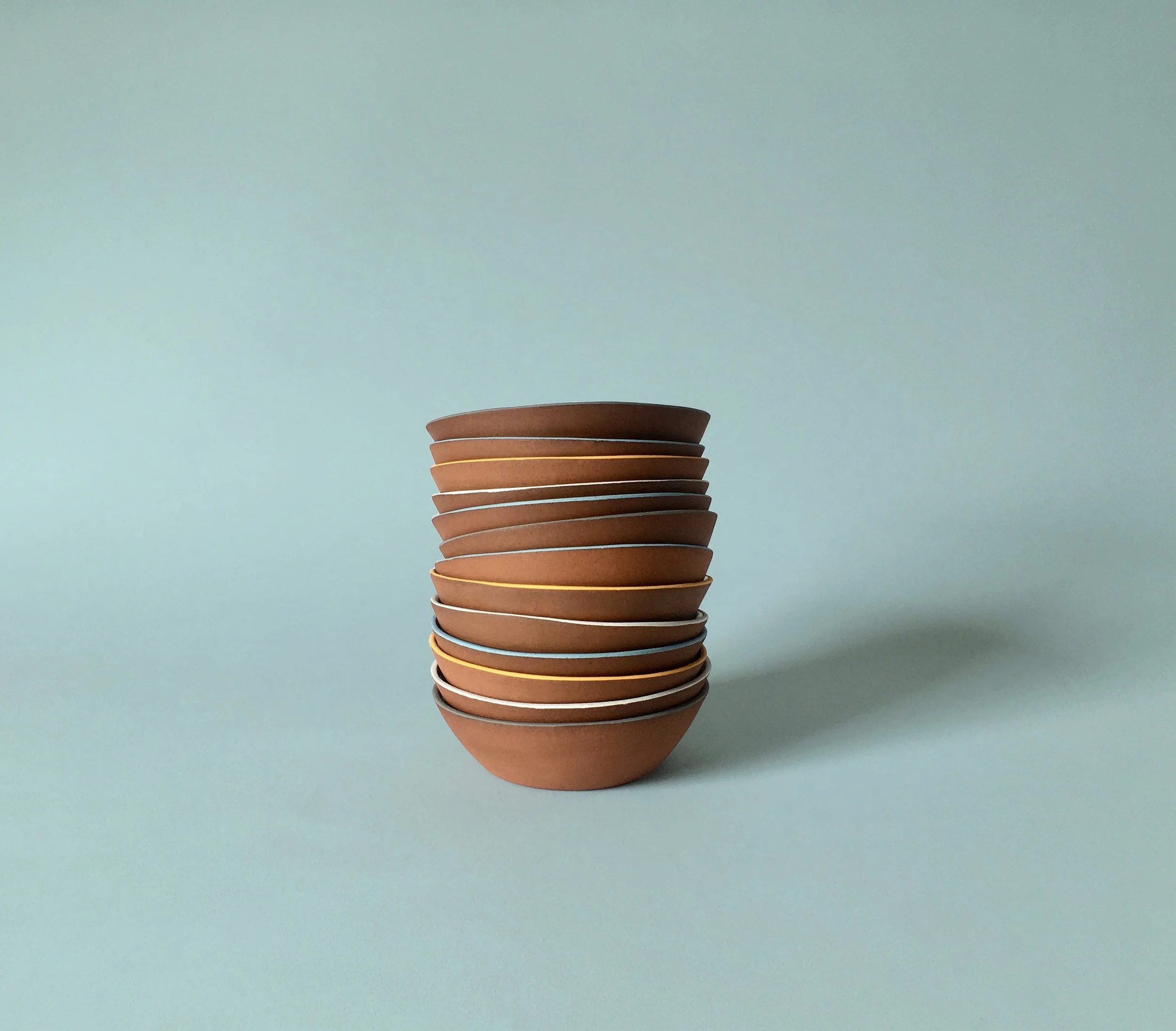 Stack of brown ceramic bowls on a pastel blue background