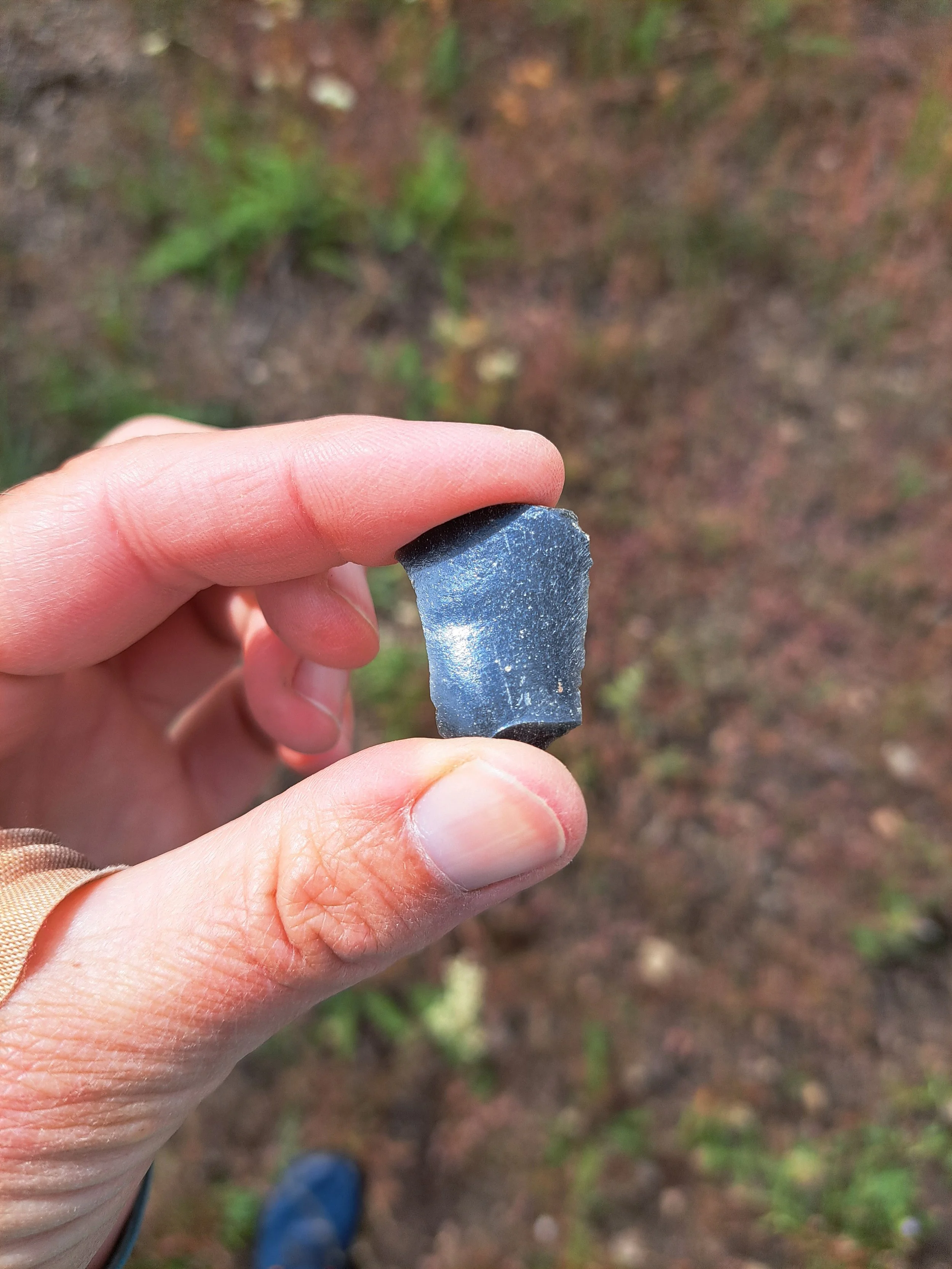 An index finger and thumb hold a small piece of rock