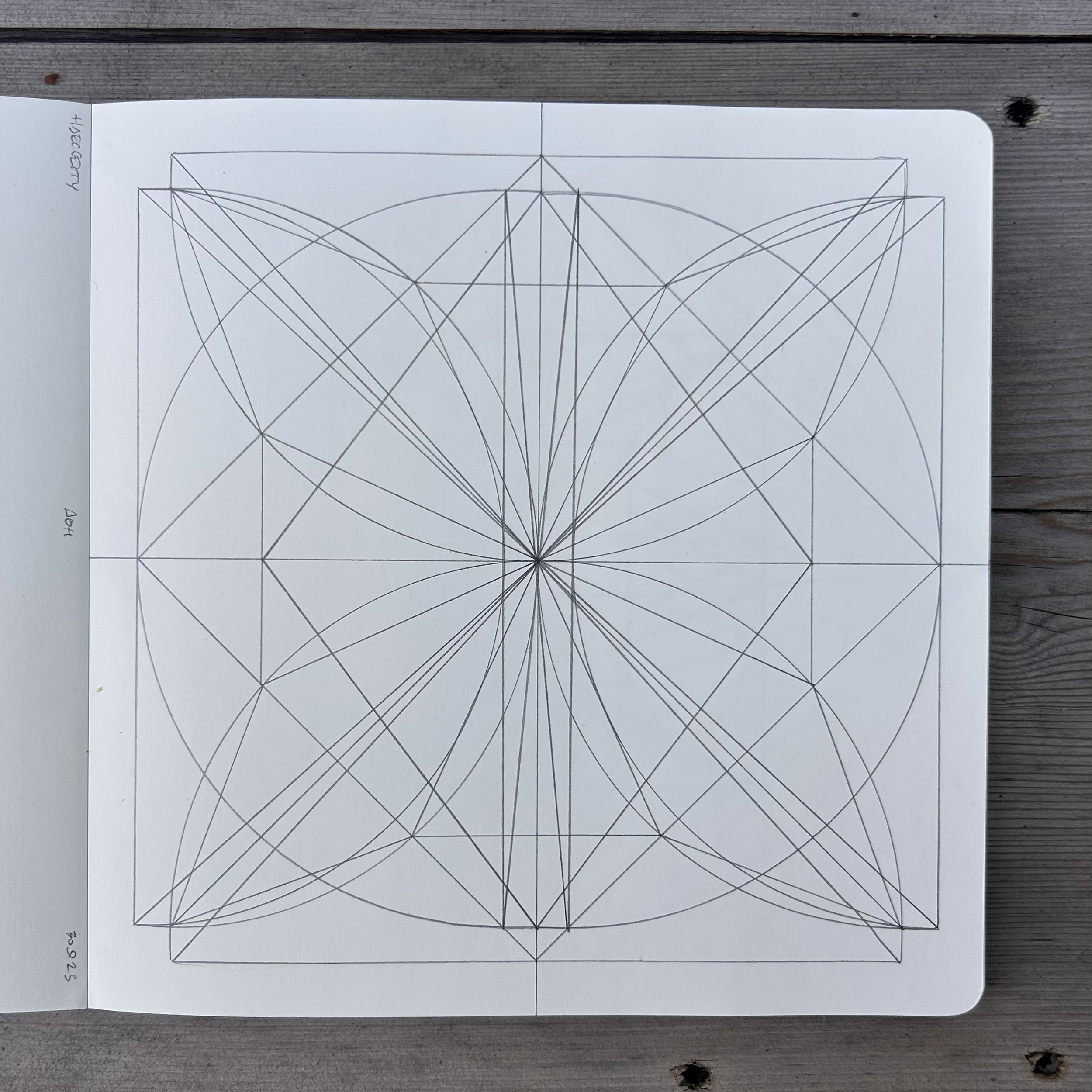 A notebook page with a geometric star pattern design made of intersecting straight lines drawn with a pencil.