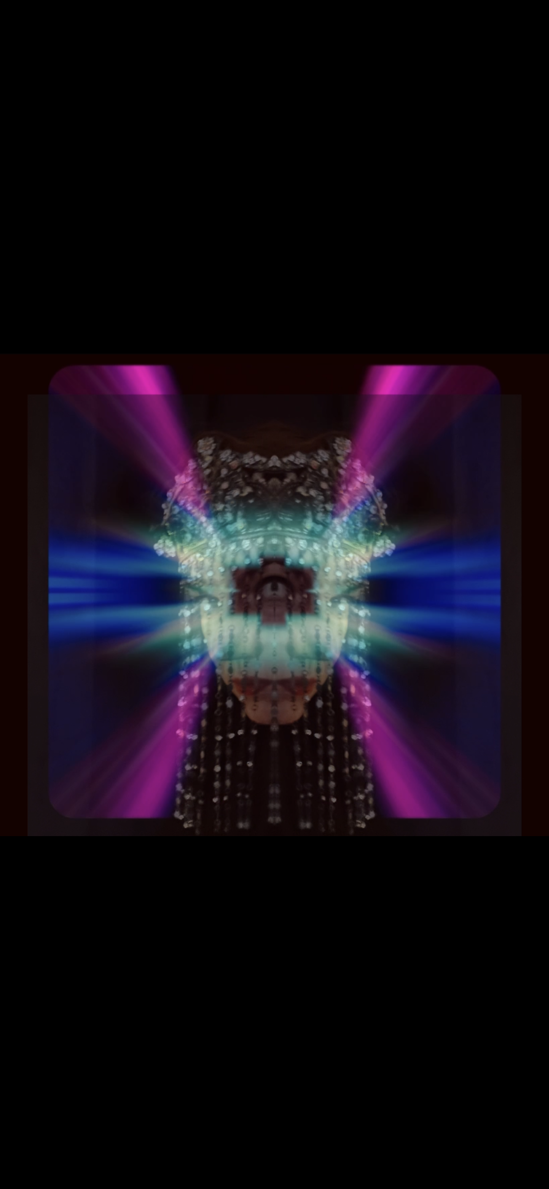 A digitally manipulated image featuring a mirrored human face with colorful laser-like light beams in pink, blue, and green radiating outward from the face amid a dark background.