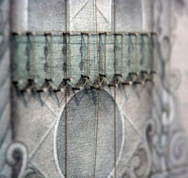 Close-up of a fabric with embroidery thread and pins being used to hold the design in place.