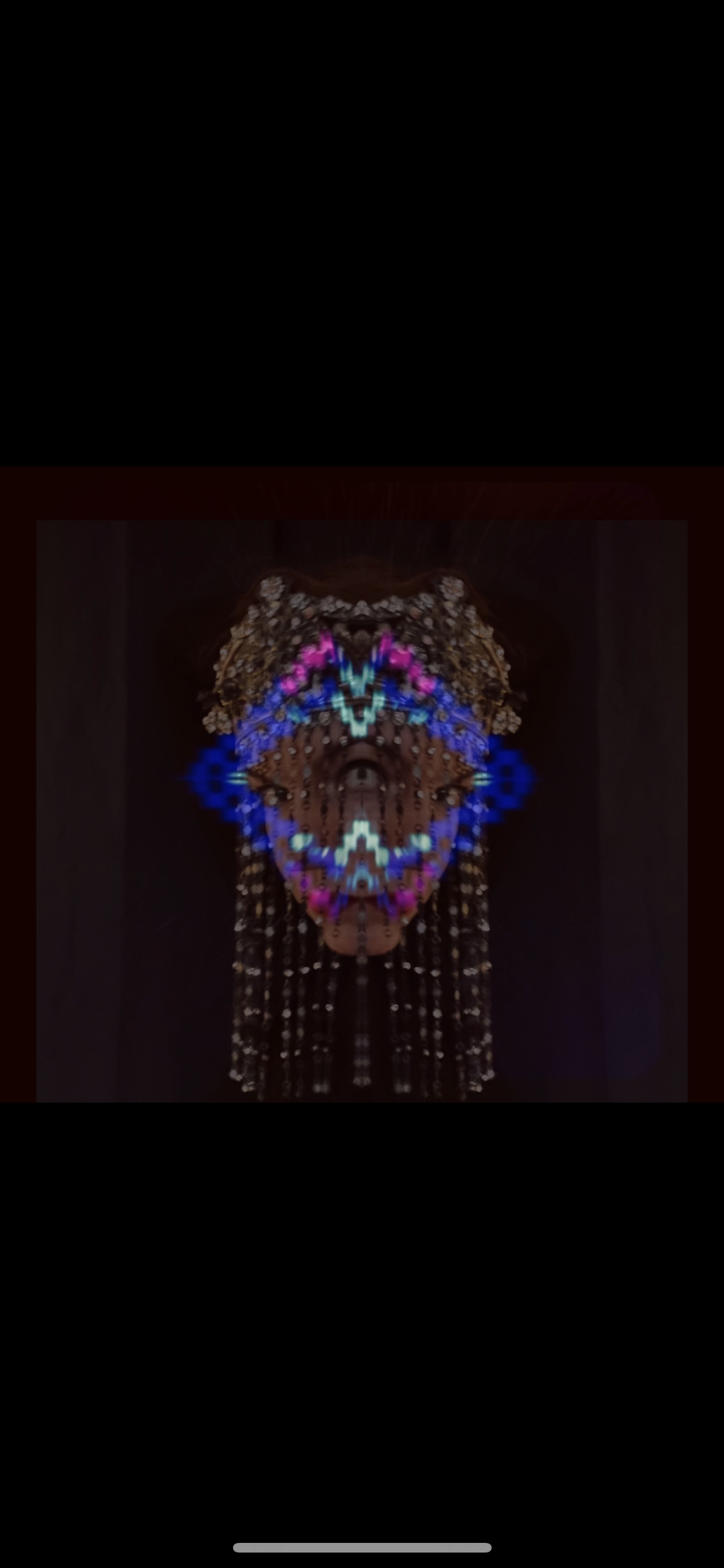 A digital art image of a face created with colorful, pixelated light patterns against a dark background, resembling a butterfly or mask.