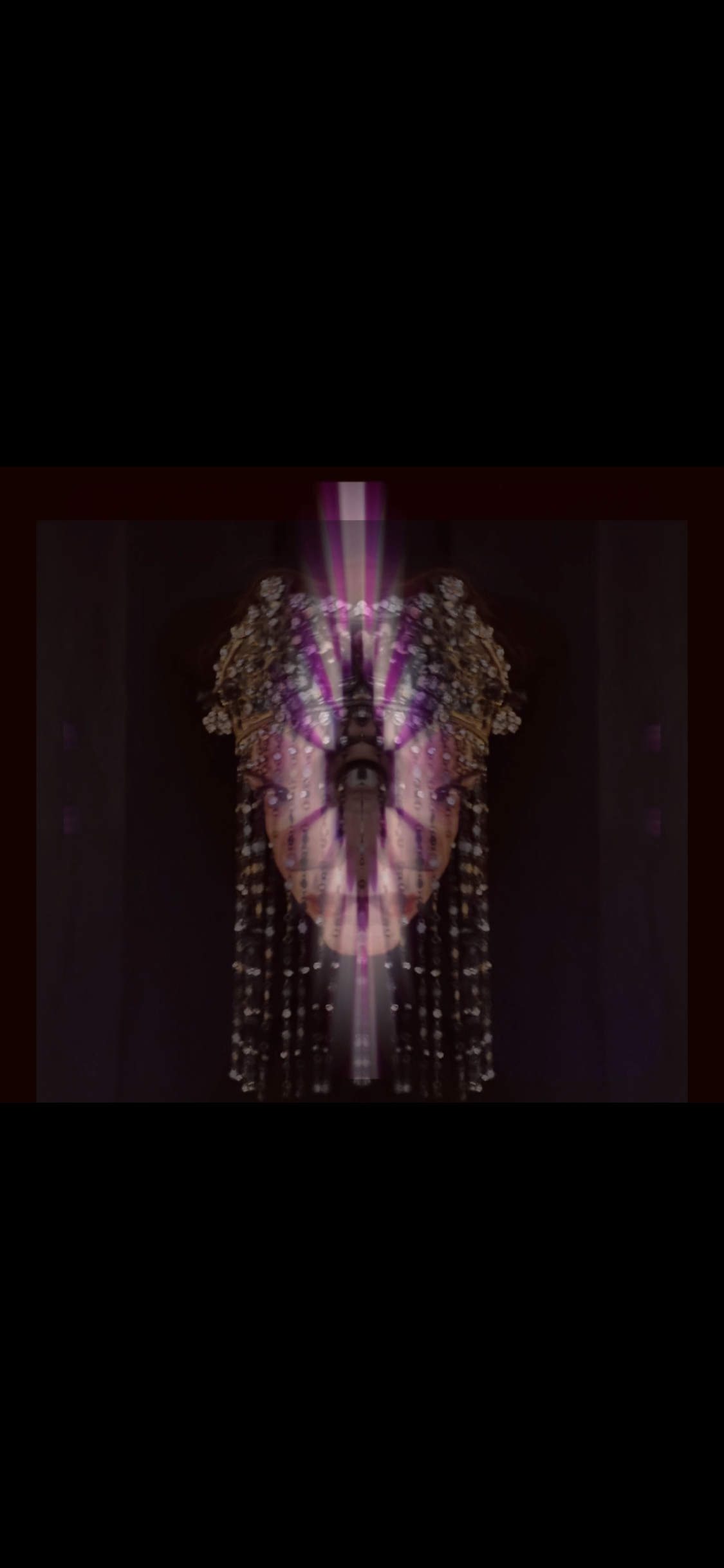 A mirrored, digitally manipulated image of a woman wearing an ornate headdress with flowers and jewelry, with purple lighting effects creating a symmetrical, abstract appearance.
