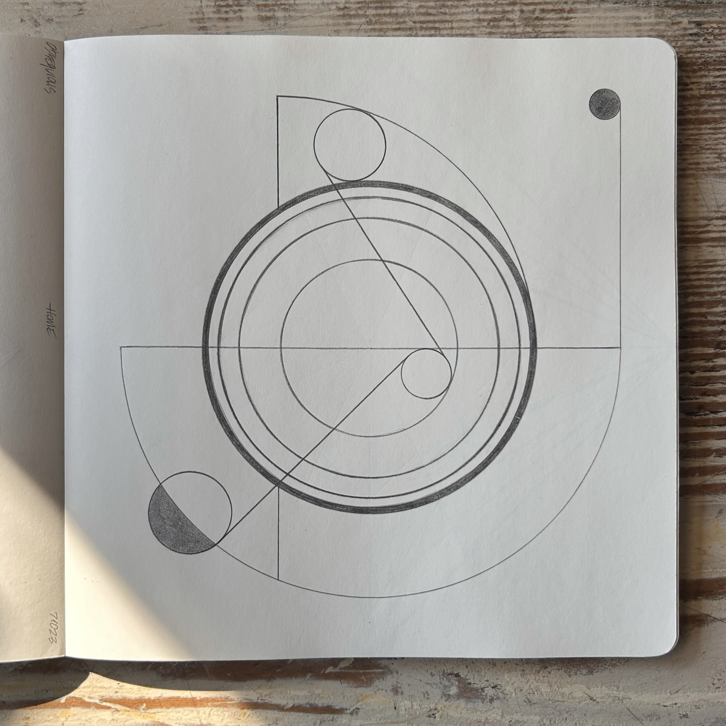 A notebook with geometric line art consisting of circles, lines, and arcs, drawn in pencil.