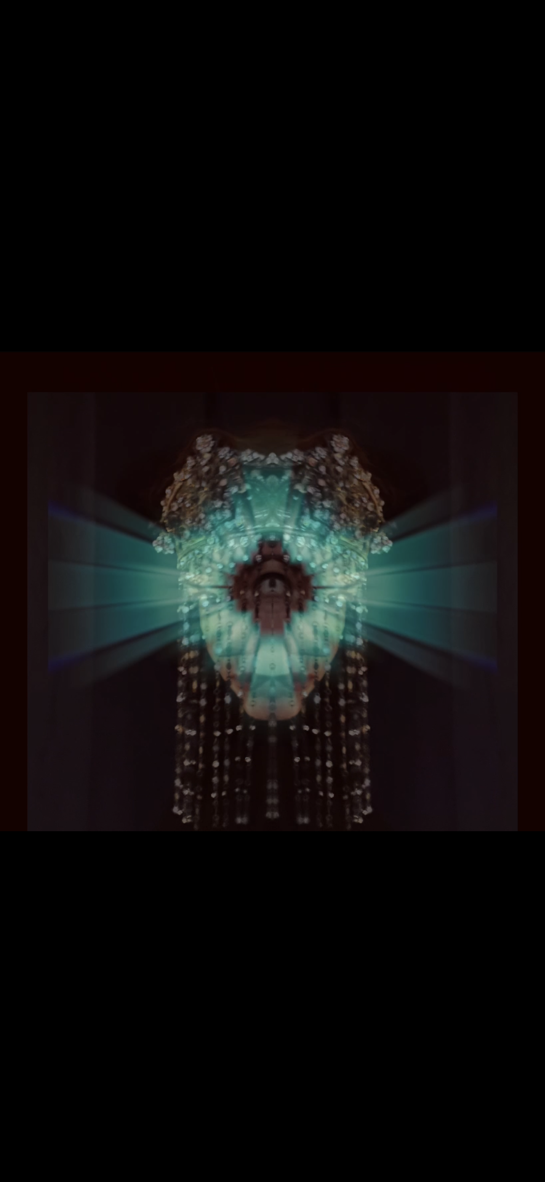 A symmetrical, kaleidoscopic digital art piece featuring a human eye at the center surrounded by glowing turquoise and gold light patterns, with dark background elements.