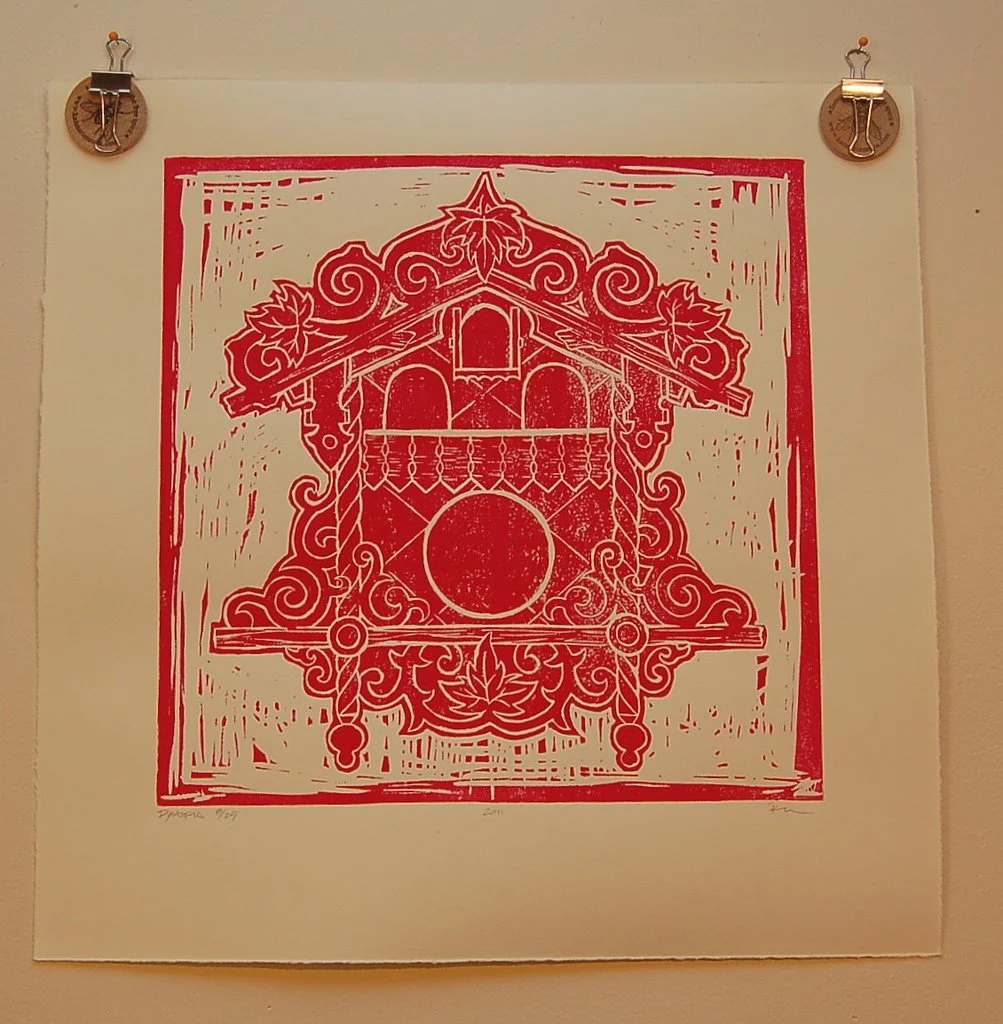 A red and white paper cutout of a decorative house with intricate scrollwork, leaves, and geometric shapes, mounted on a wall.