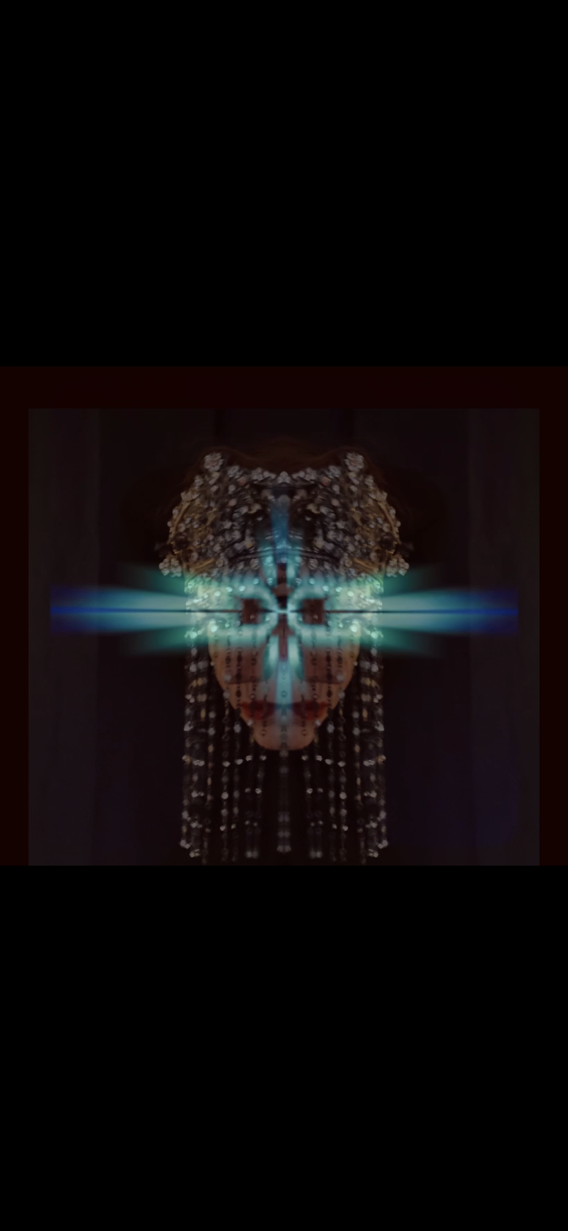 A highly stylized, mirrored digital artwork of a person's face, featuring a symmetrical design with blue light effects and floral patterns surrounding the head.