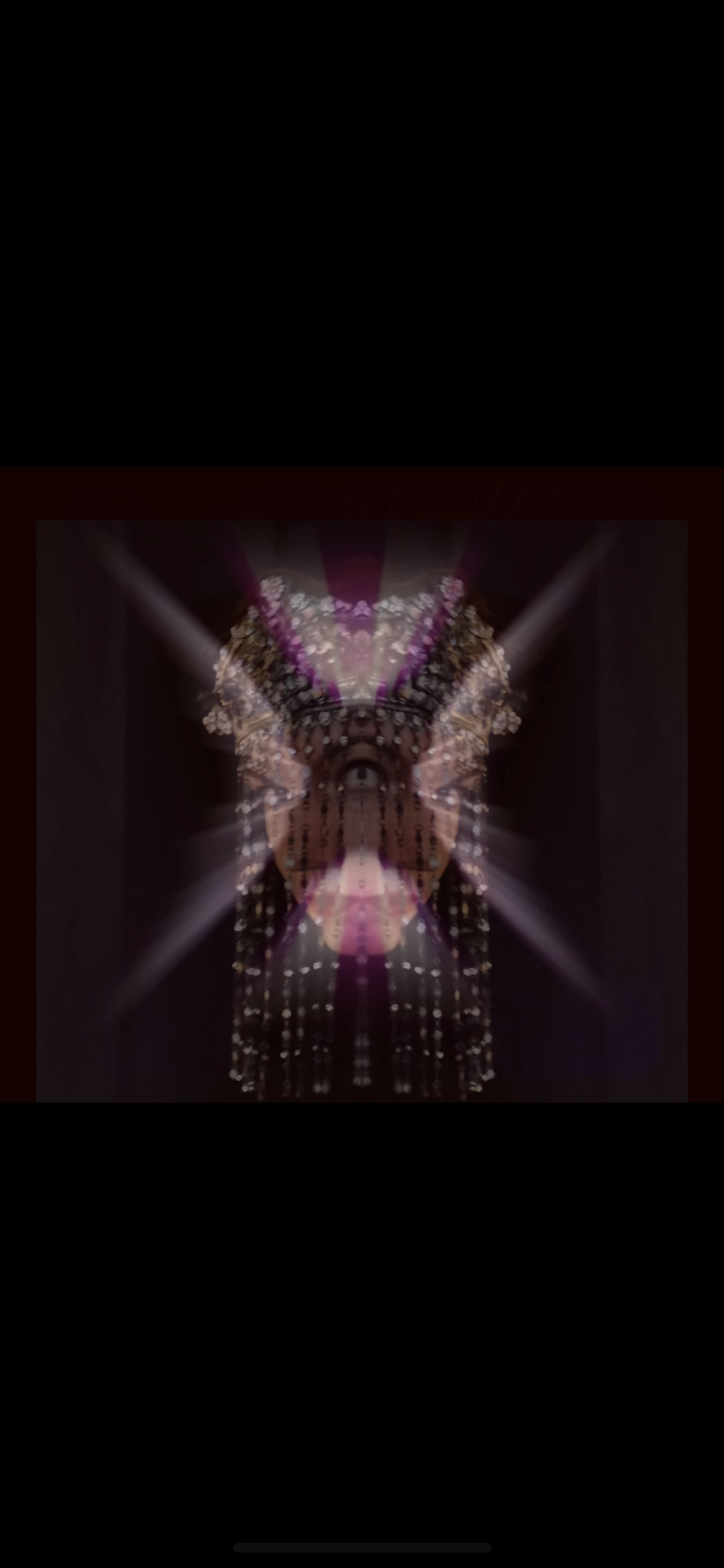A digitally manipulated image creating a symmetrical, kaleidoscope-like effect featuring a person wearing a decorative headdress and jewelry, with bright lights and floral accents.