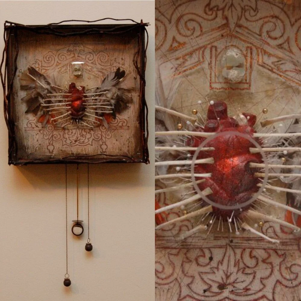 Mixed media art piece featuring a red heart with multiple white sticks or rods extending outward, set against an ornate, patterned background.