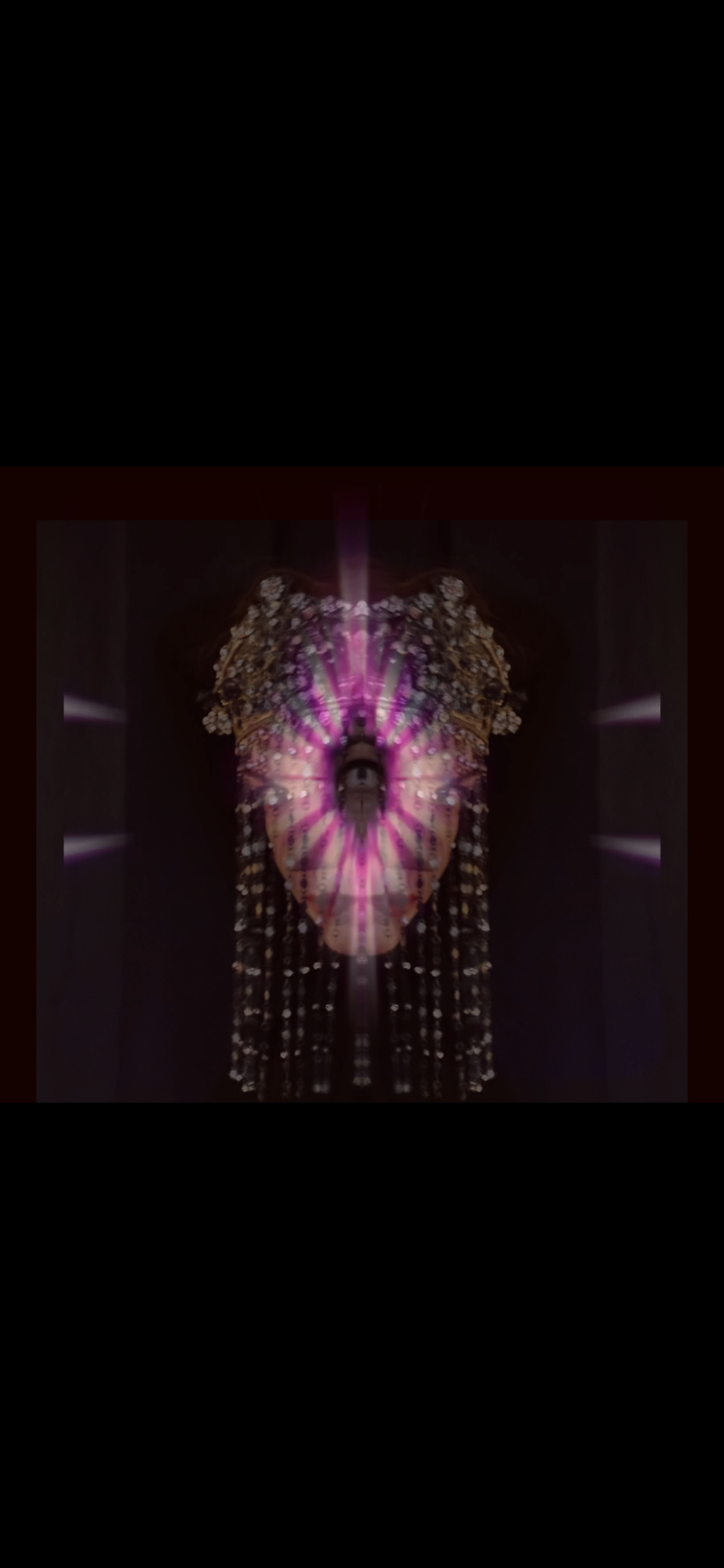 A surreal mirrored digital art featuring a face with long hair, surrounded by vibrant pink and purple light effects and floral elements, set against a dark background.