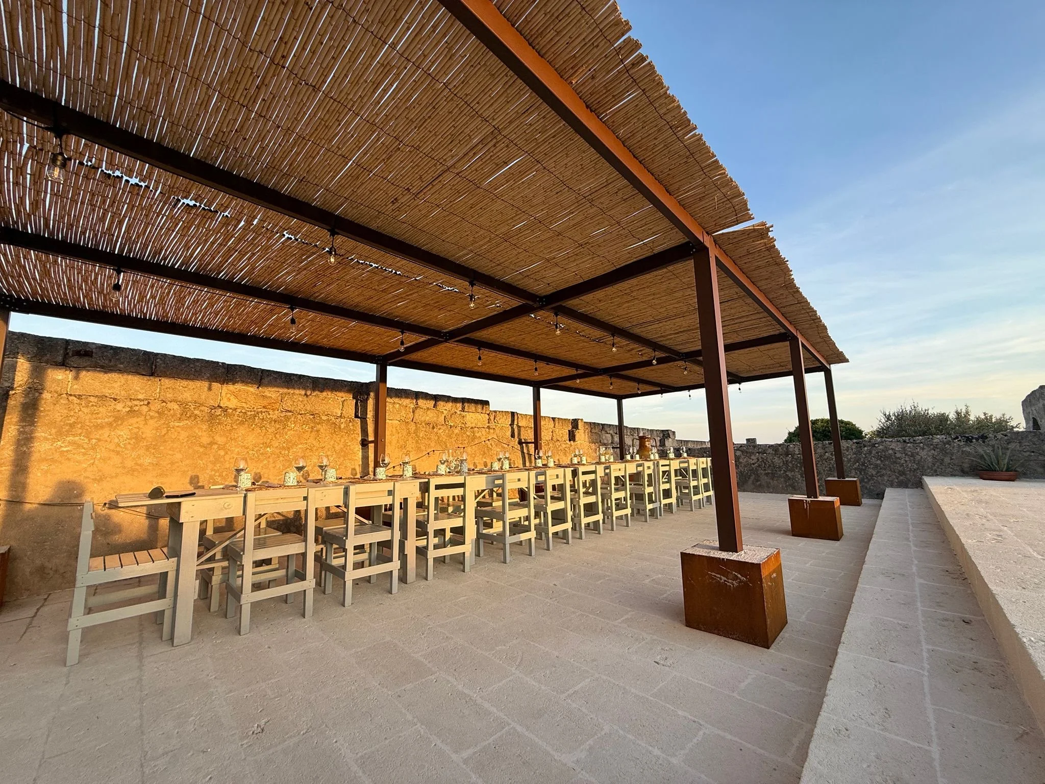 Shaded outdoor dining area under a pergola at Masseria Specula, surrounded by countryside views and ideal for communal retreat meals in southern Italy