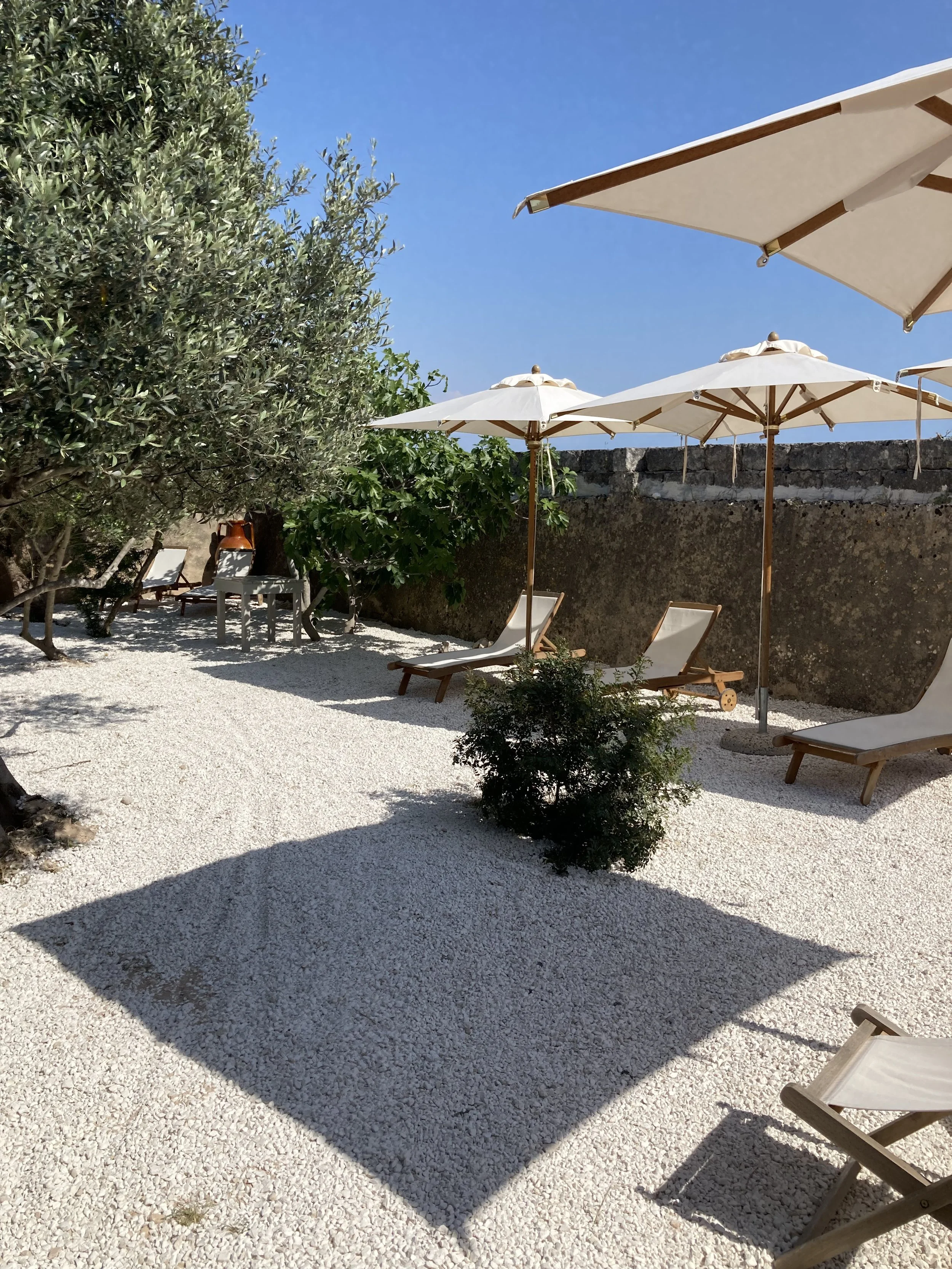 Shaded relaxation area at Masseria Specula featuring soft seating and natural surroundings, ideal for rest between yoga sessions in Puglia