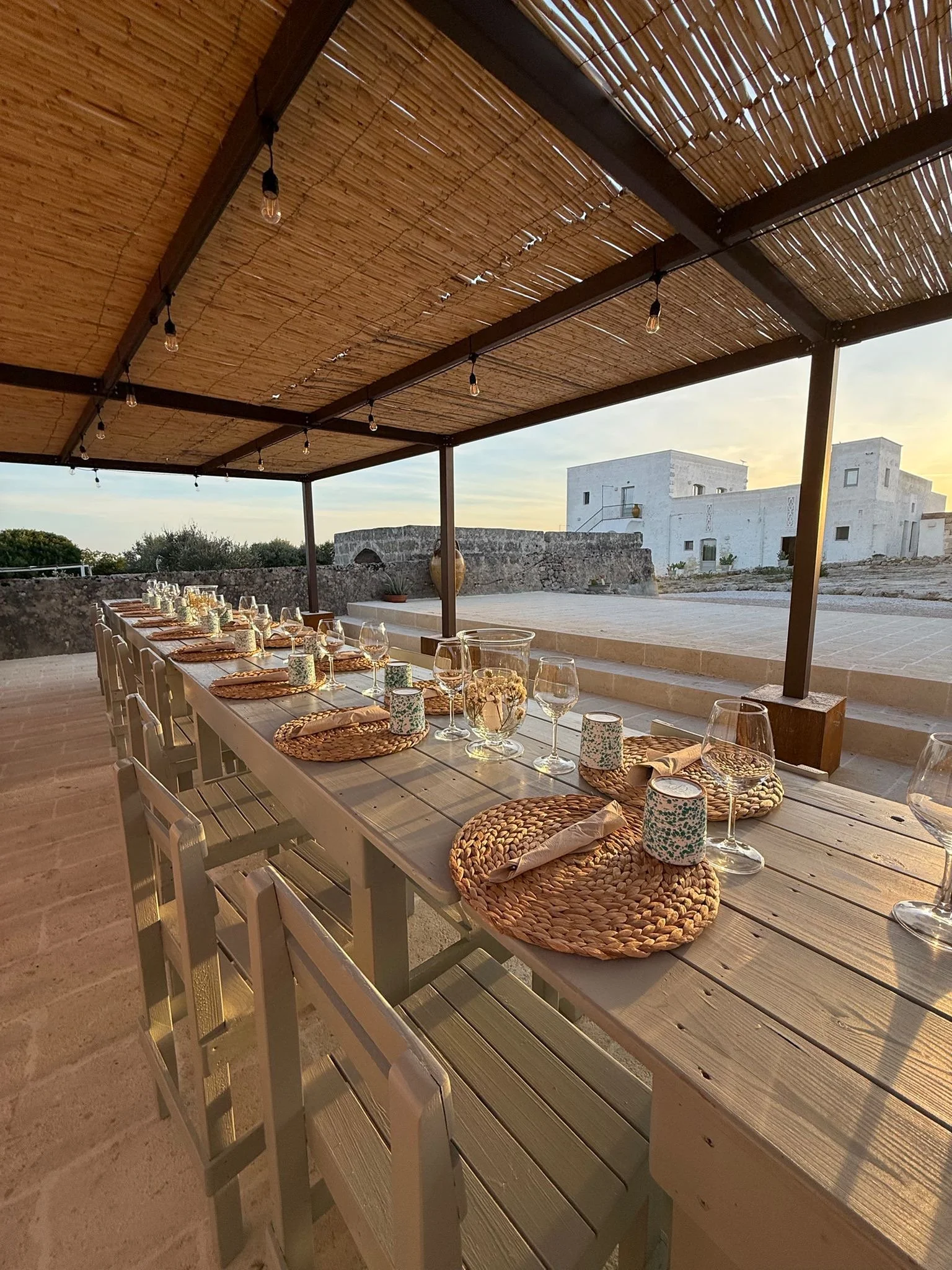 Rustic table setting under a pergola at Masseria Specula featuring natural materials, soft light, and an authentic Italian outdoor dining experience