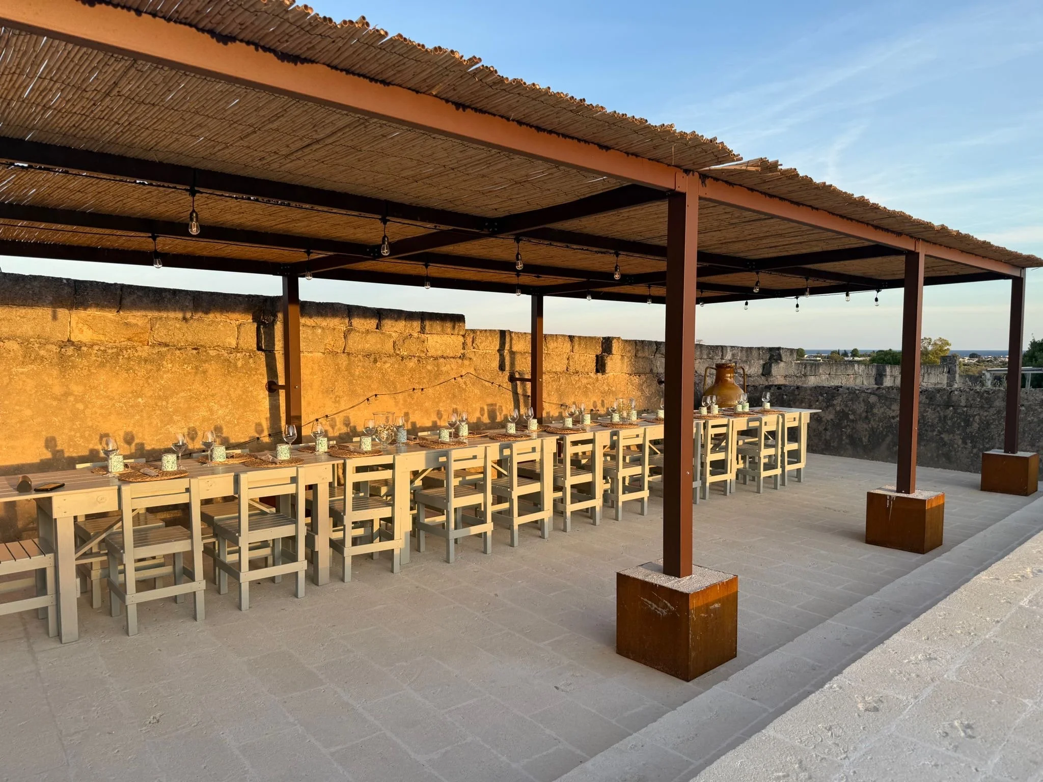 Outdoor dining under a pergola at sunset at Masseria Specula, with warm lighting and a relaxed atmosphere for retreat gatherings in Italy