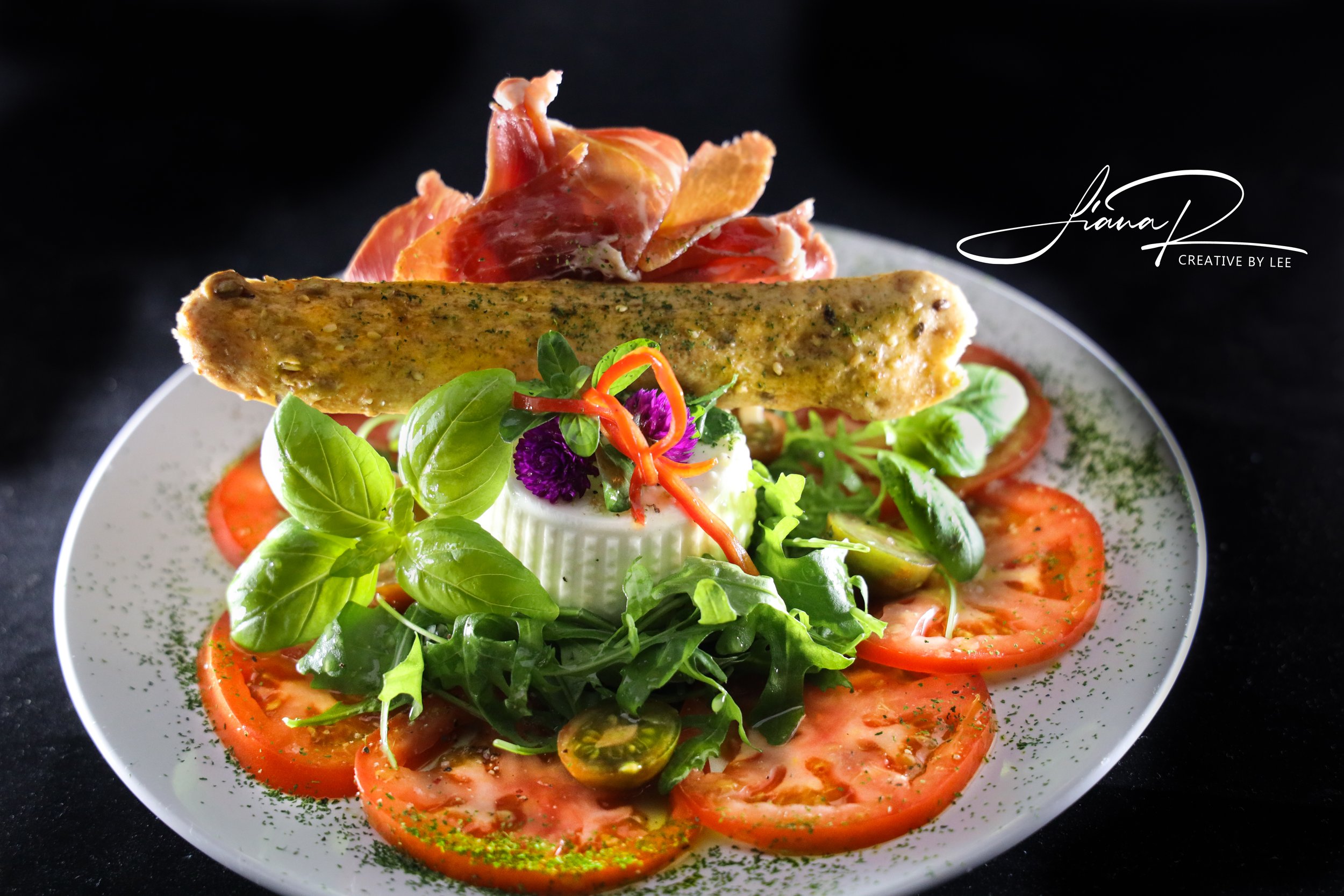 Ensalada con burrata ahumada, tomate fresco y rúcula, un elegante plato italiano creado por un chef profesional en el Algarve, Portugal.