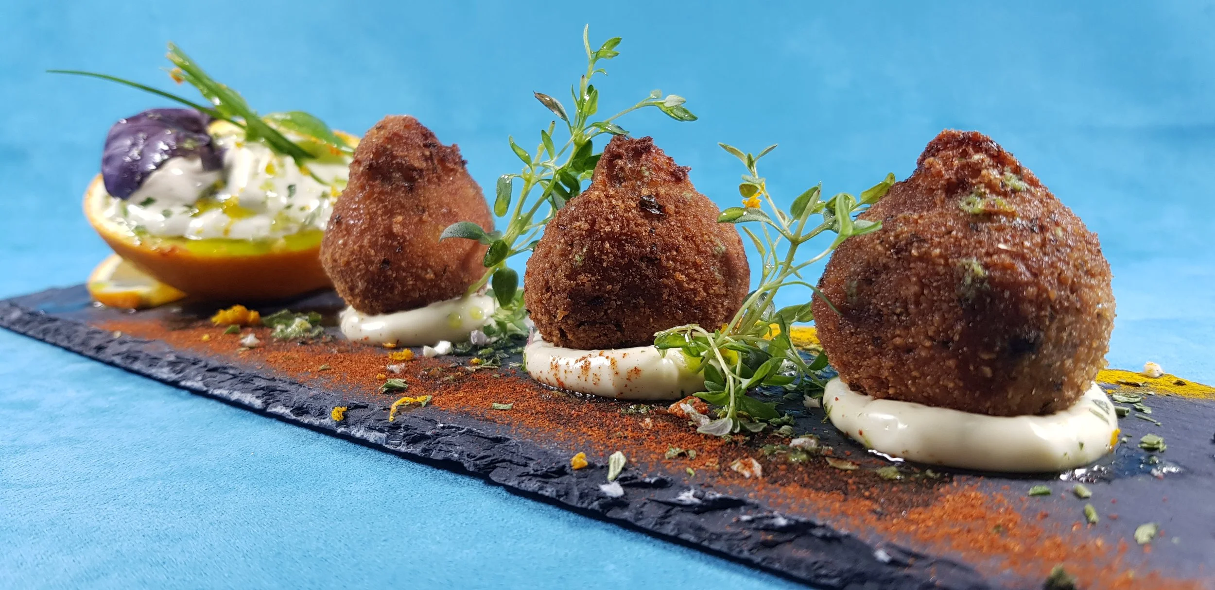 Bocadito crujiente de alheira algarvia con crema de naranja y hierbas frescas, creación del chef en el Algarve.