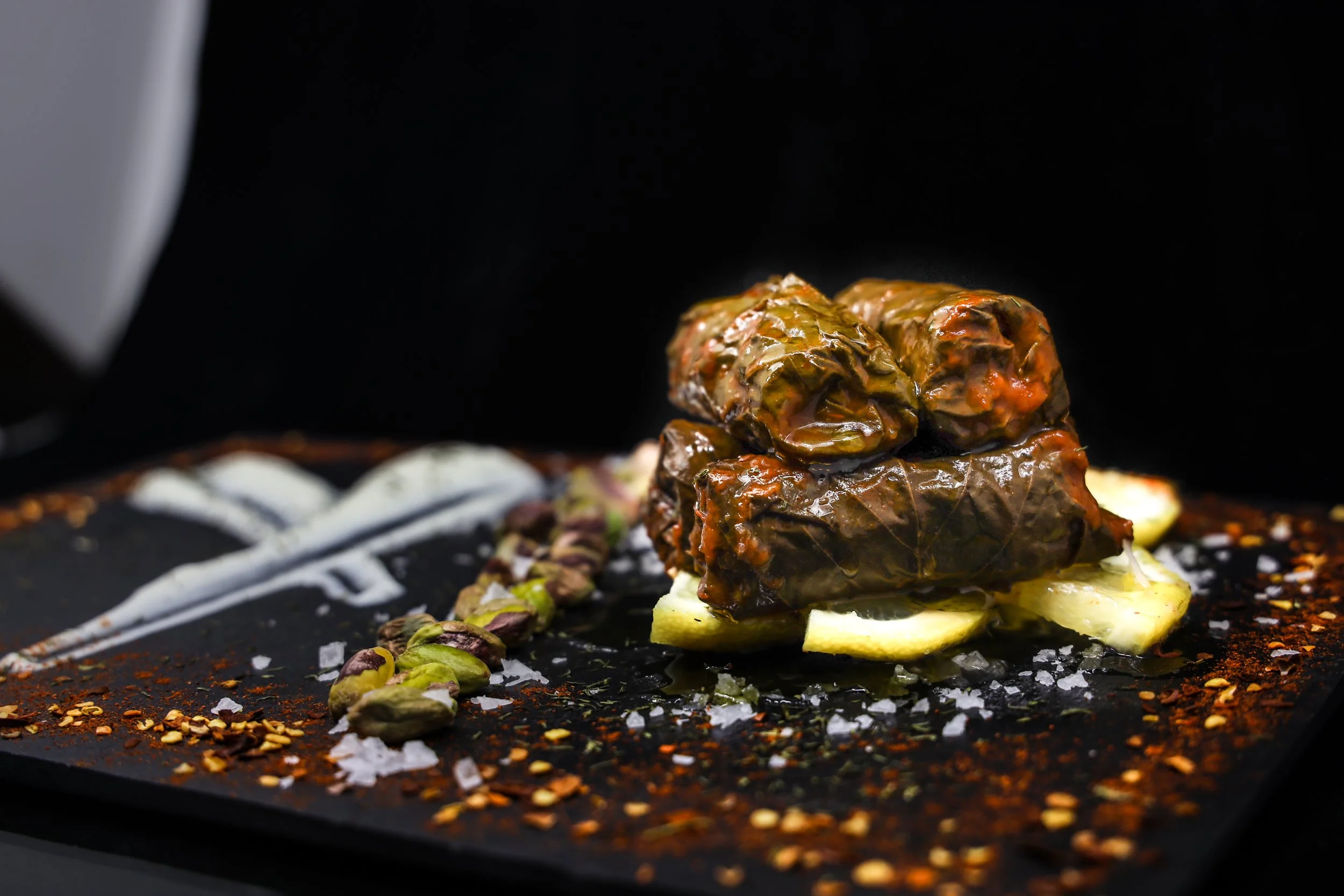 Dolmades griegos rellenos de arroz, servidos con limón y salsa tzatziki.