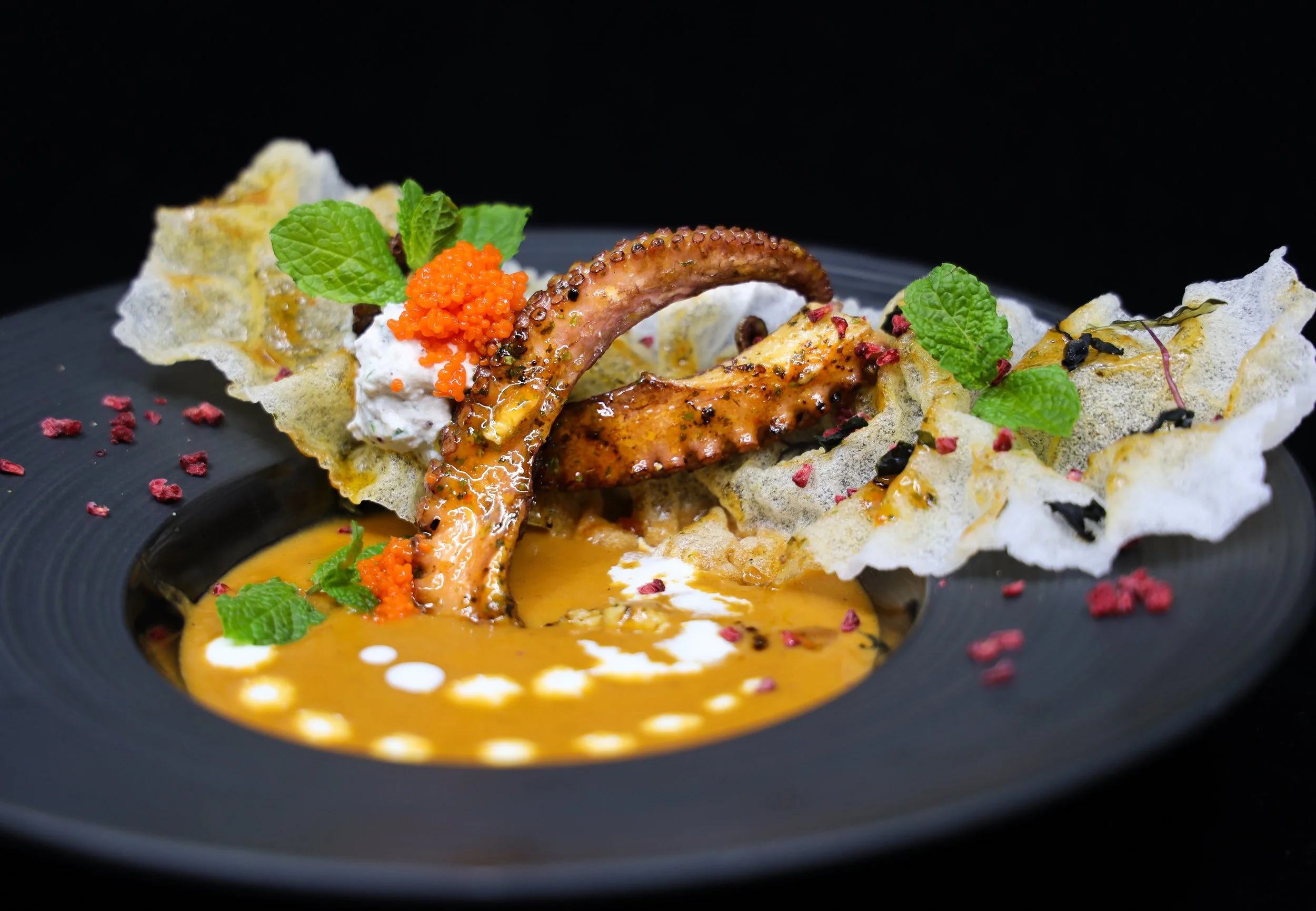 Pulpo tierno sobre bisque de marisco con crujiente y notas de chim, plato de mar creado por un chef profesional en el Algarve, Portugal.