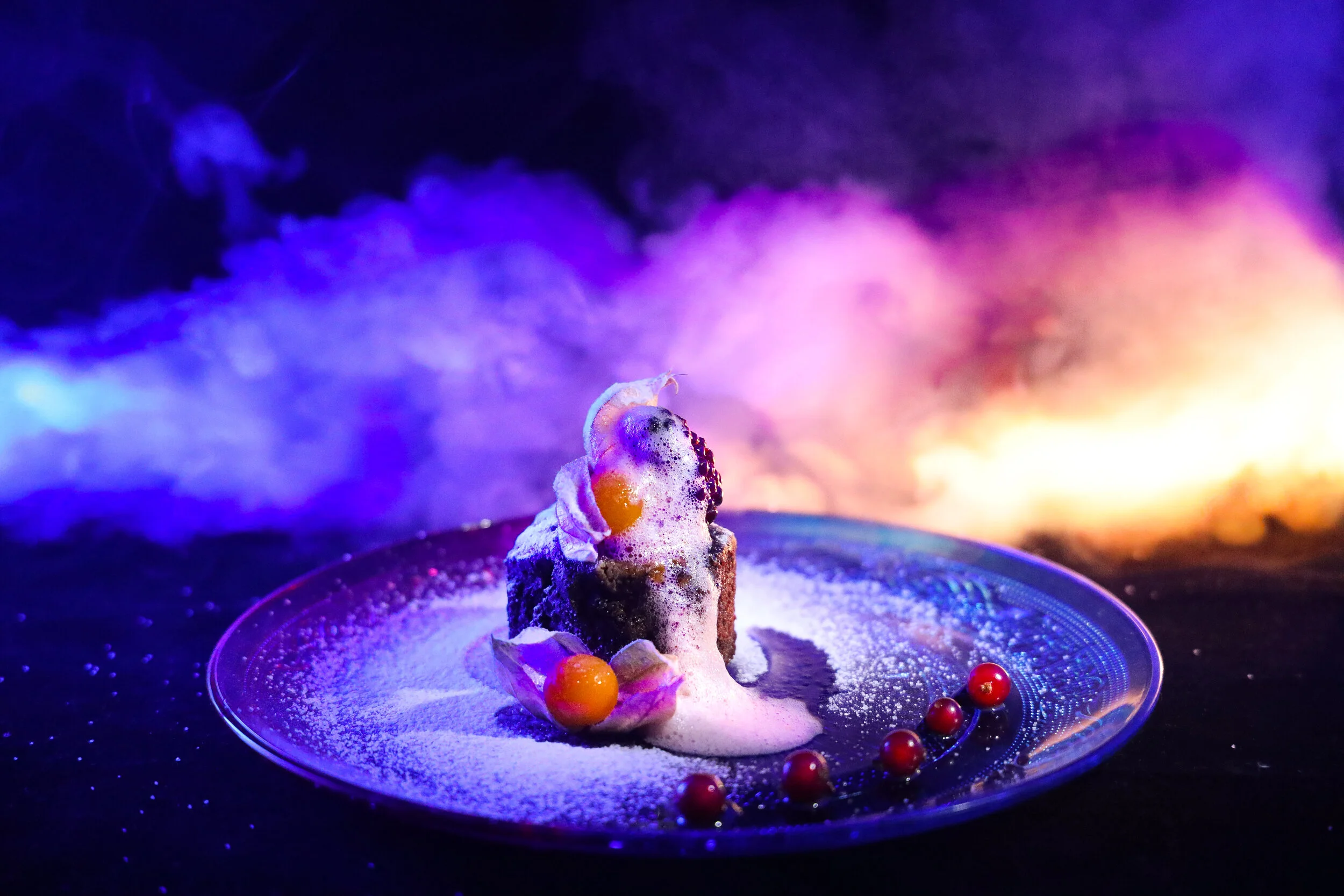 Brownie gourmet con haba tonka y crema delicada, postre creativo con presentación artística e iluminación dramática.