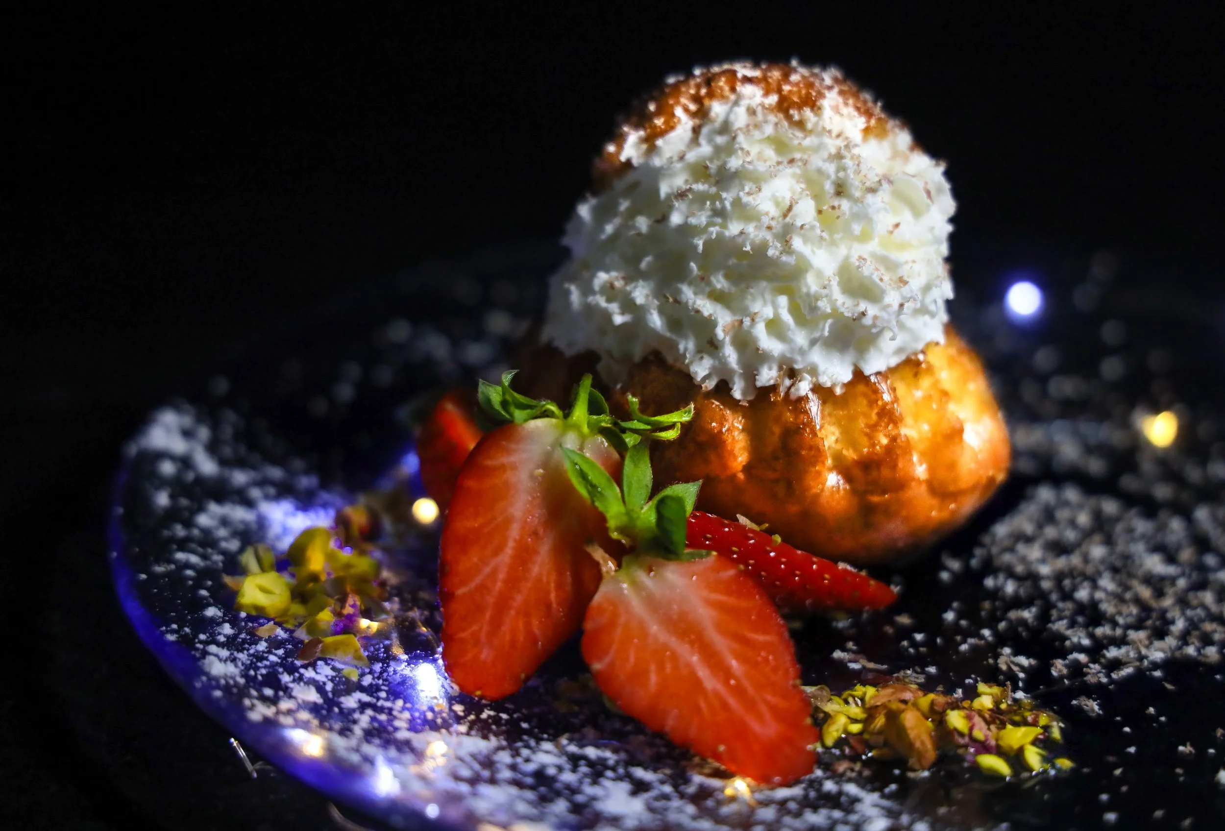 Baba al ron tradicional con nata montada y fresas frescas, postre clásico de alta pastelería.