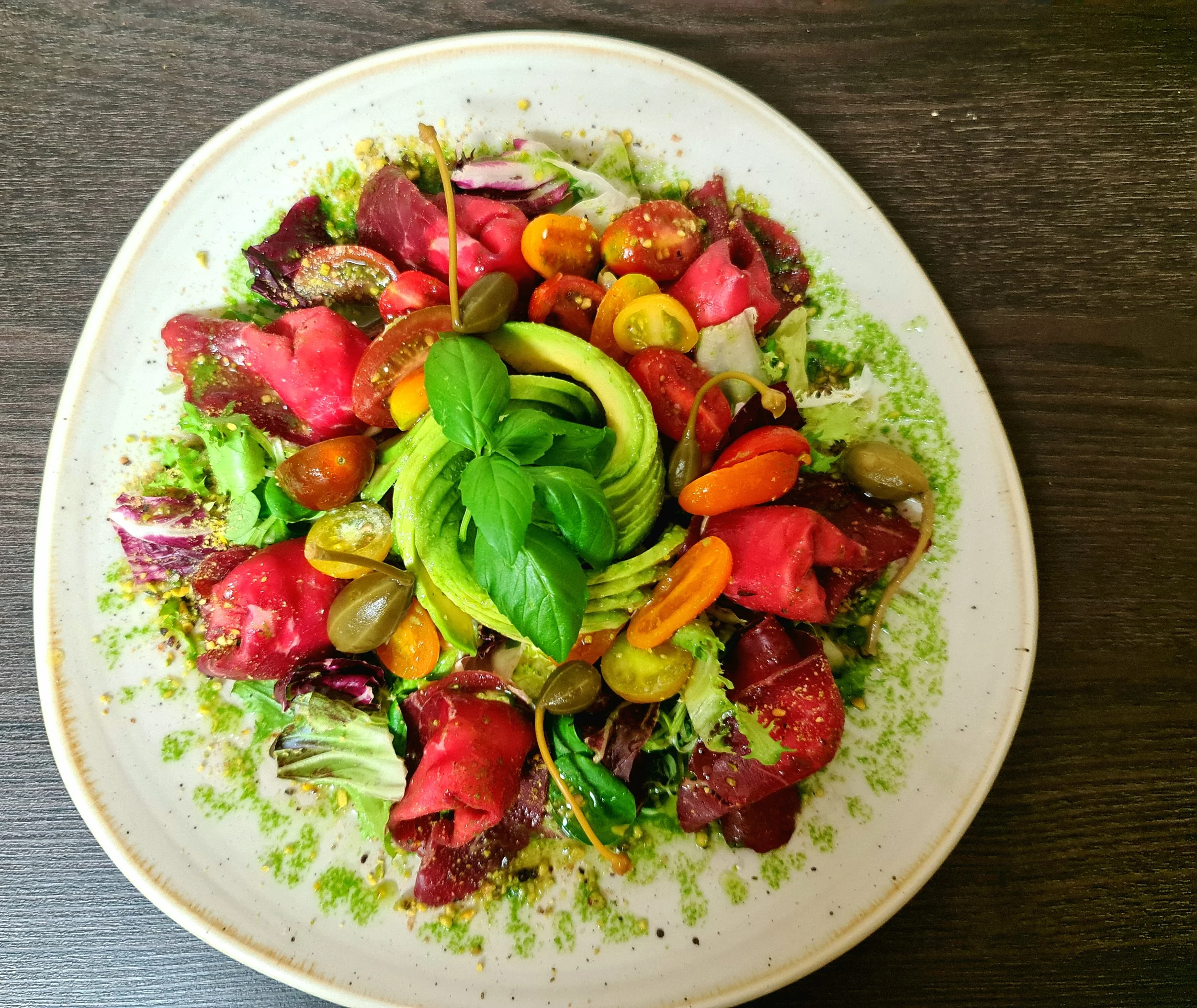 Carpaccio fino con espiral de aguacate, tomates cherry y hierbas frescas, entrante gourmet creado por un chef profesional en el Algarve, Portugal.