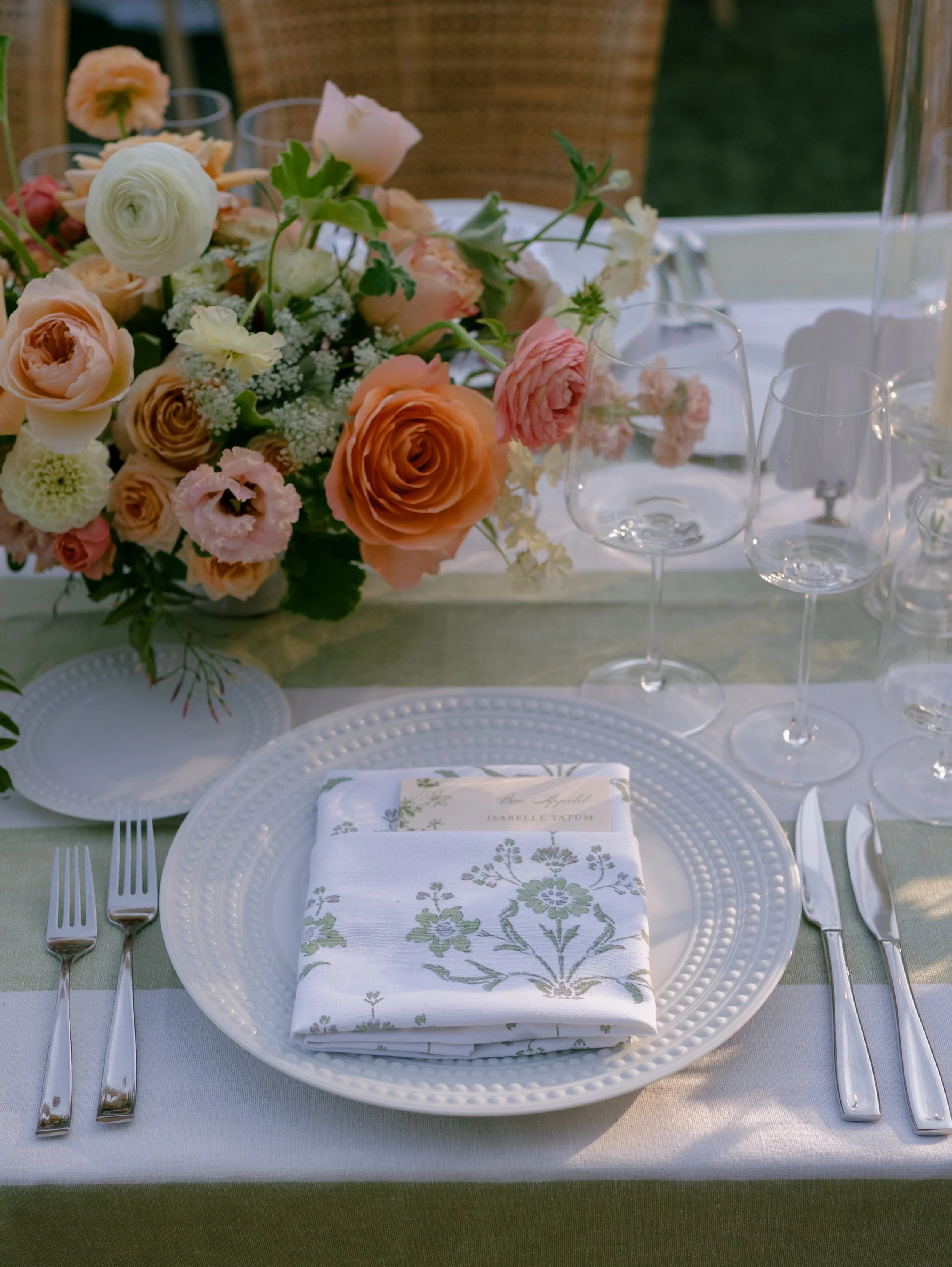 Tabletop design with perla china, green and white striped linens, custom napkins, and bright florals for a wedding at Brindare in Saint Helena, California
