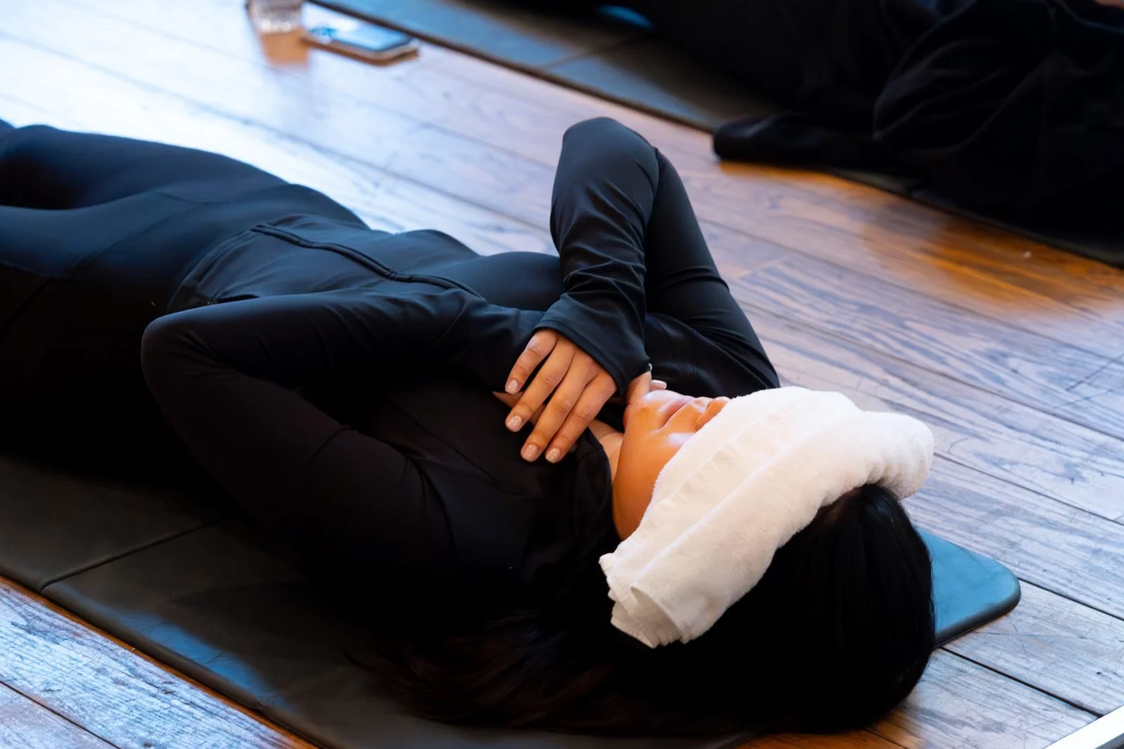 Woman resting on a mat with an eye pillow during a sound bath