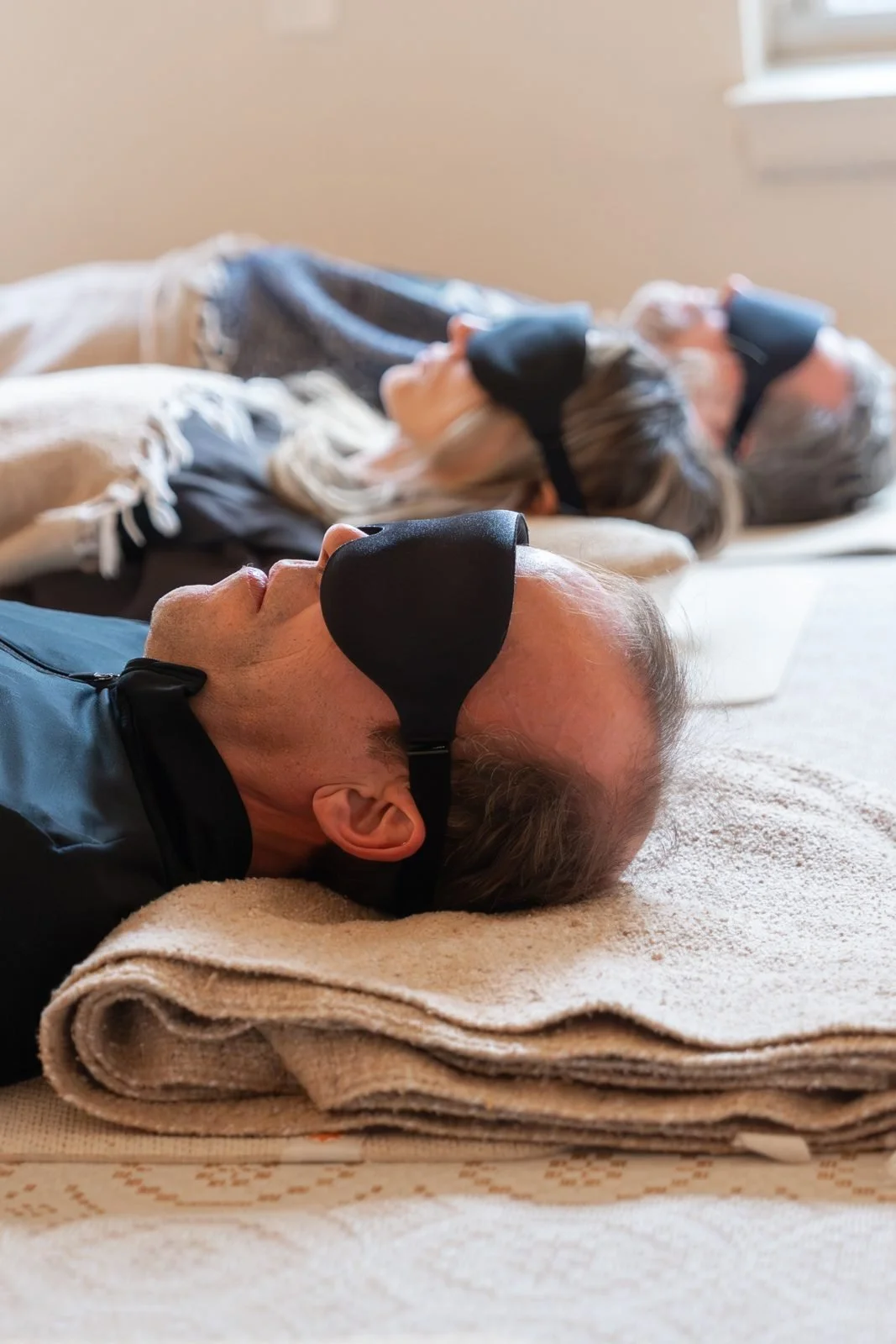 Sound bath participants resting with eye masks on blankets during a calm sound healing session