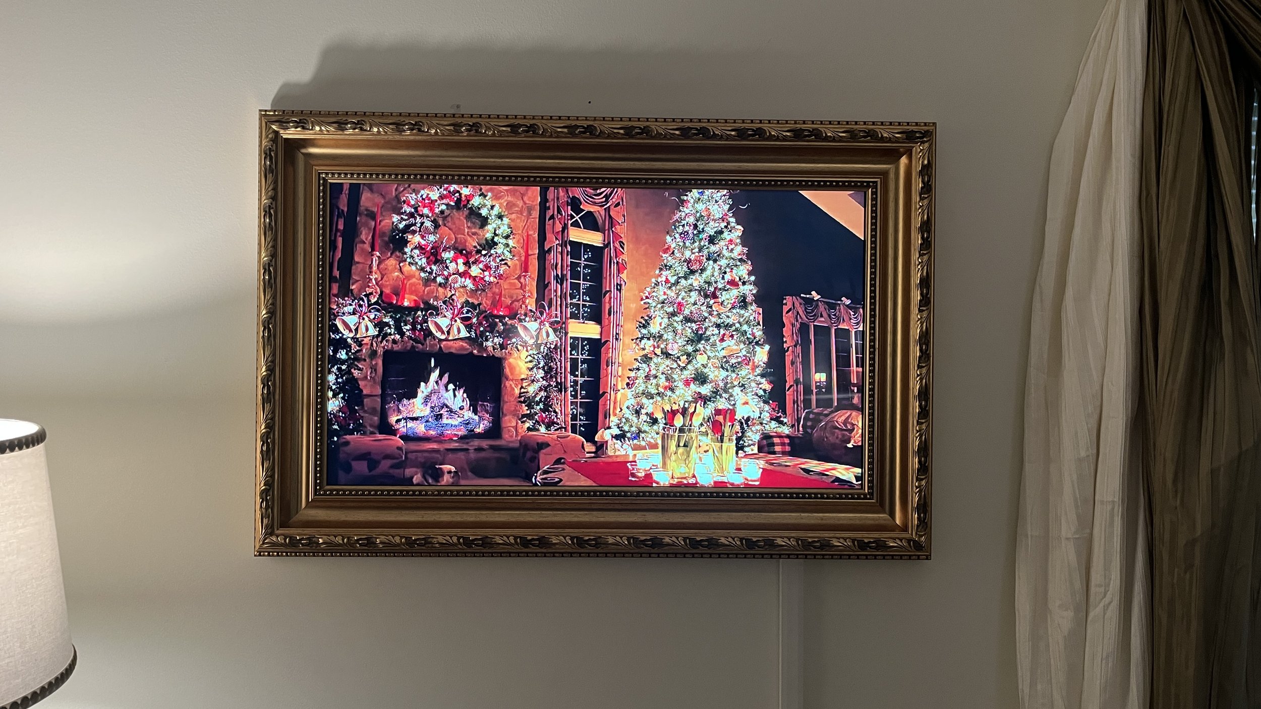A framed picture of a cozy, decorated Christmas living room with a Christmas tree, fireplace, and holiday decorations.